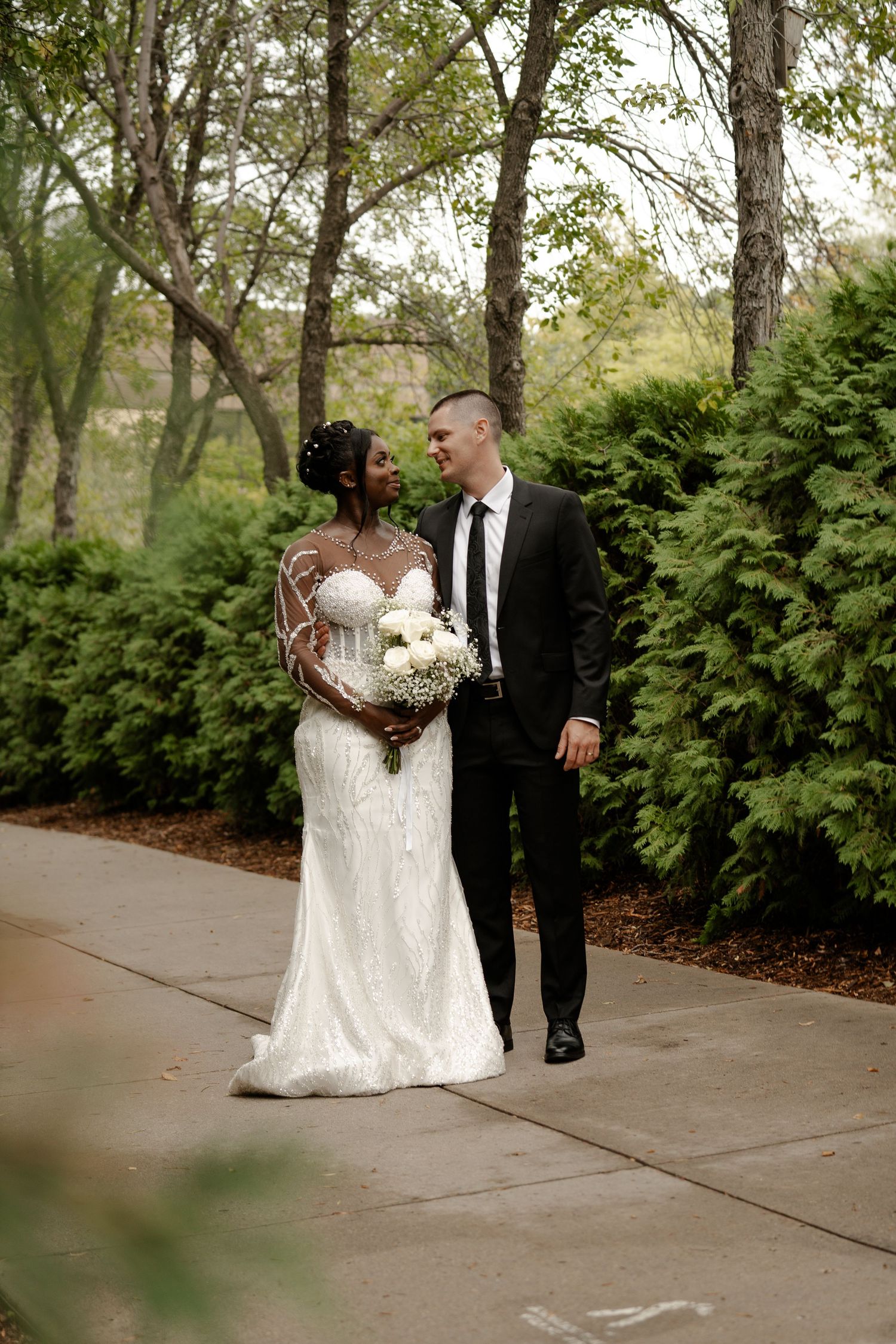 Wedding couple shares romantic moments on a tree-lined pathway at the University of Saskatchewan.