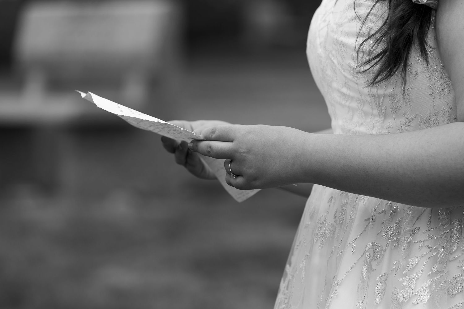 Close-up of hands holding papers during an outdoor ceremony.