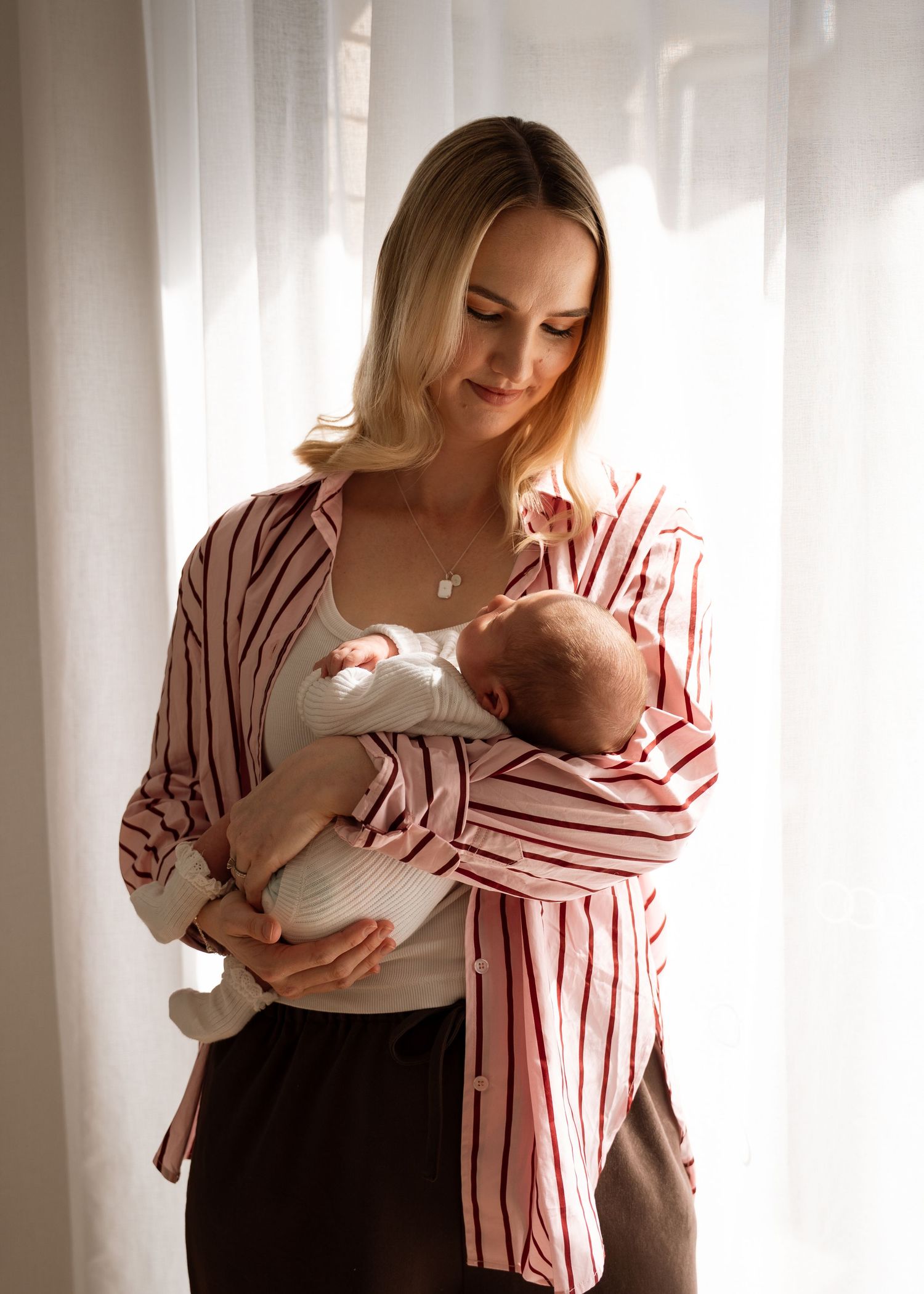 A newborn photography session at a family home. A mother with her 2 week old baby girl.