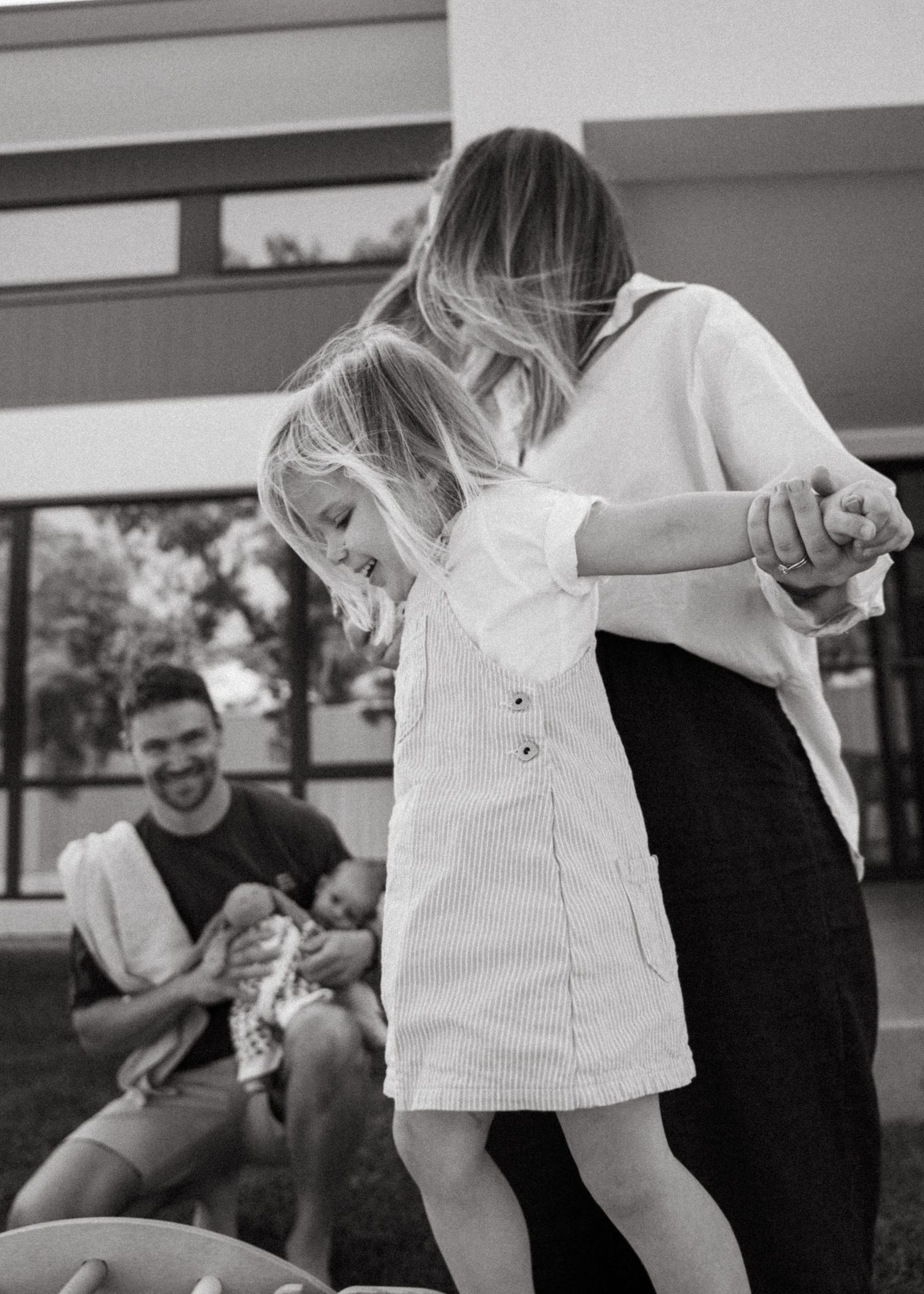 A mother and her toddler daughter playing and laughing at a family newborn photoshoot at their family home.