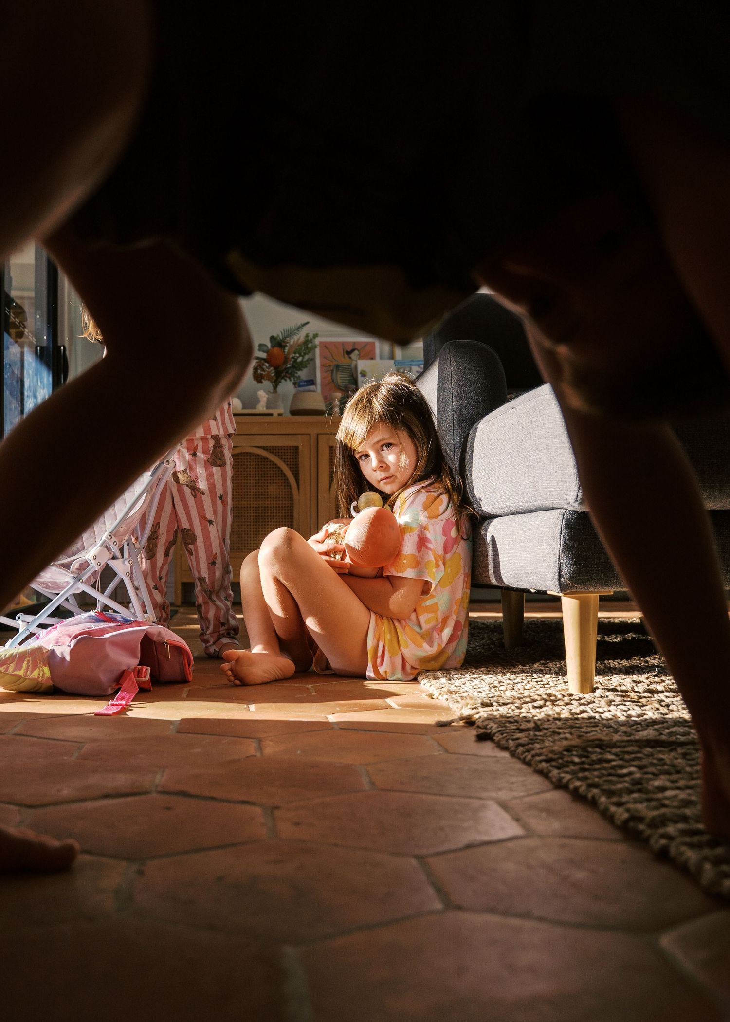 Young child playing at home in the morning sun with her dolls.