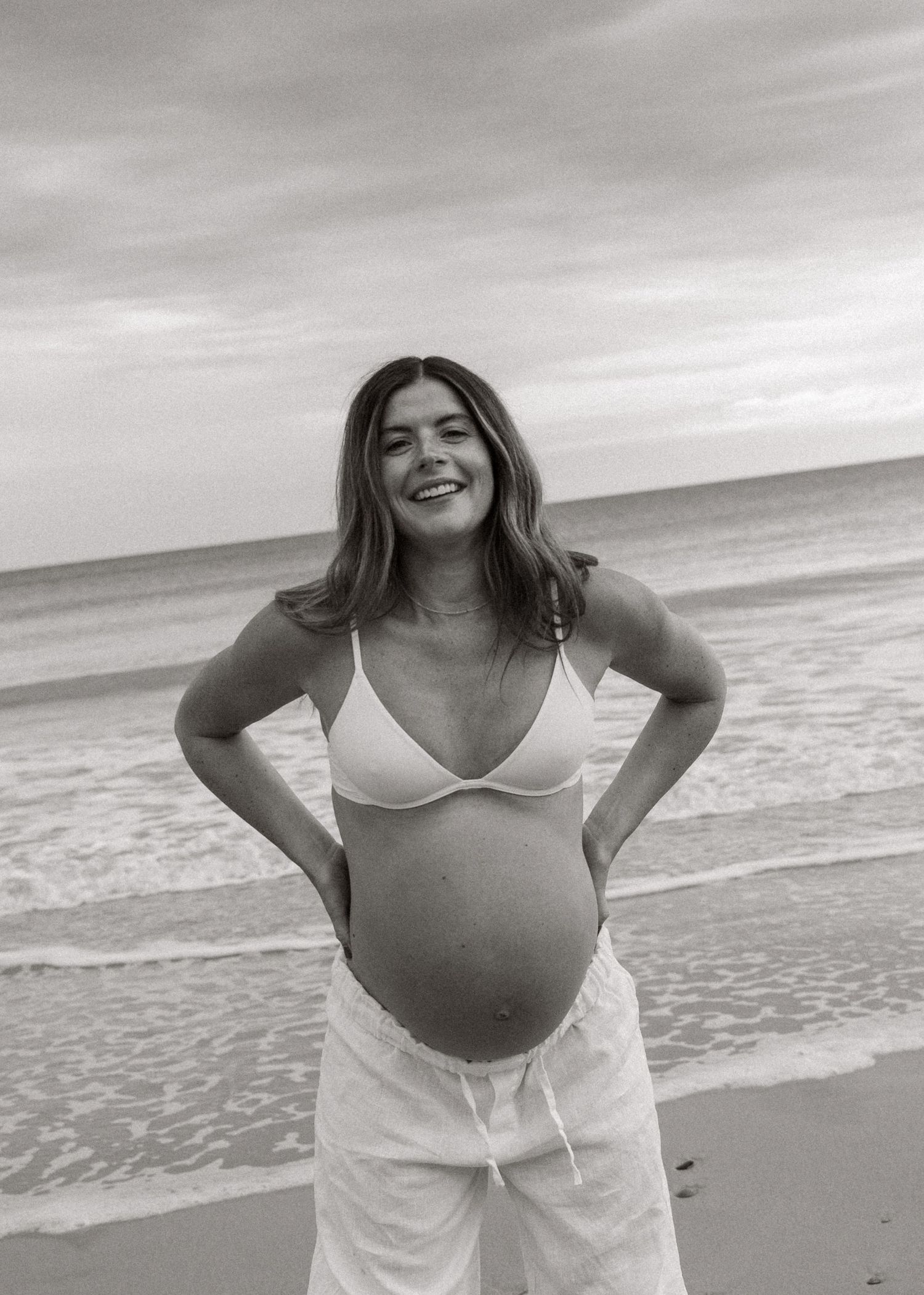 An Adelaide mother at a maternity photoshoot at the beach at golden hour.