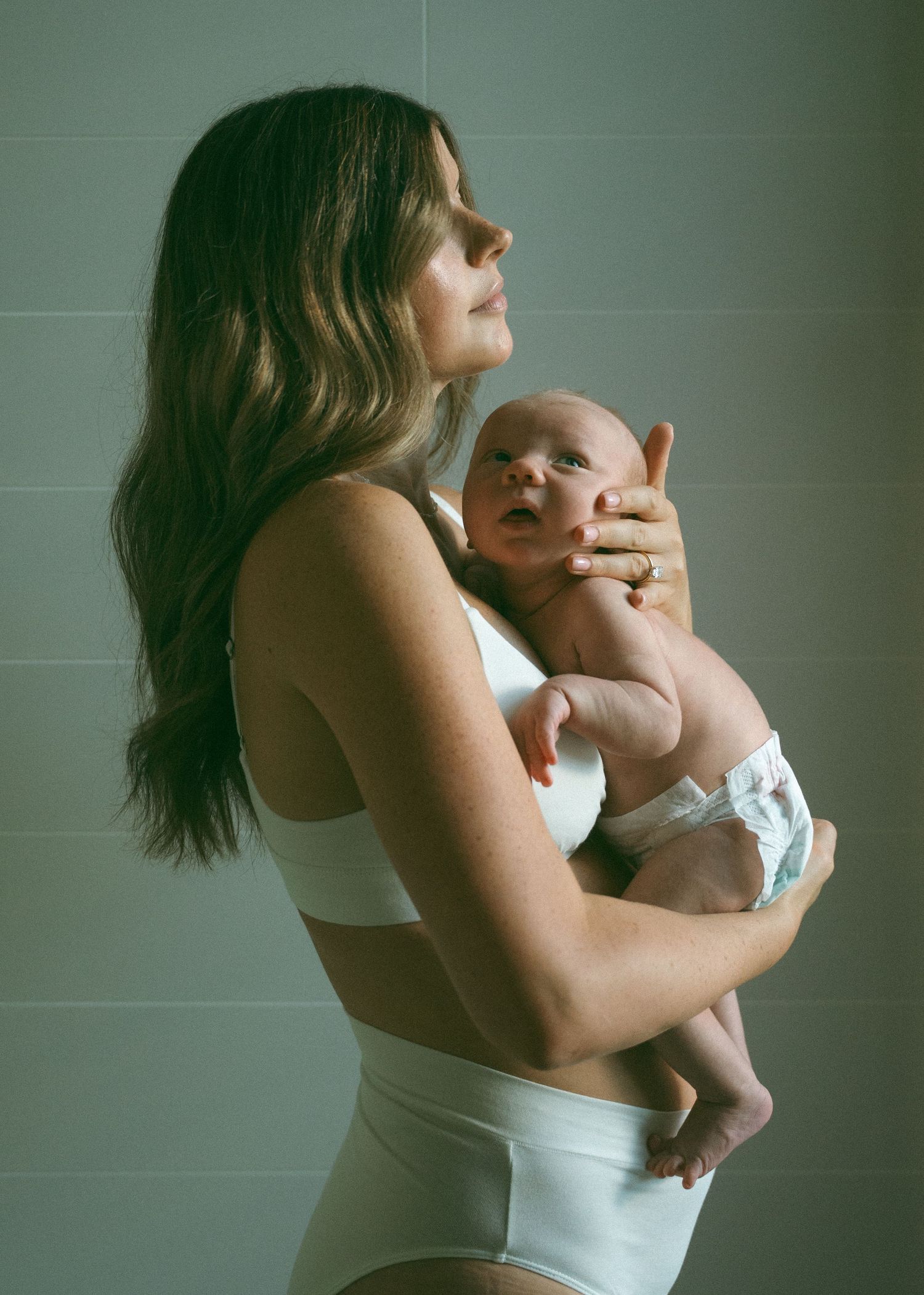 A mother and her newborn baby at a newborn photography session at home.