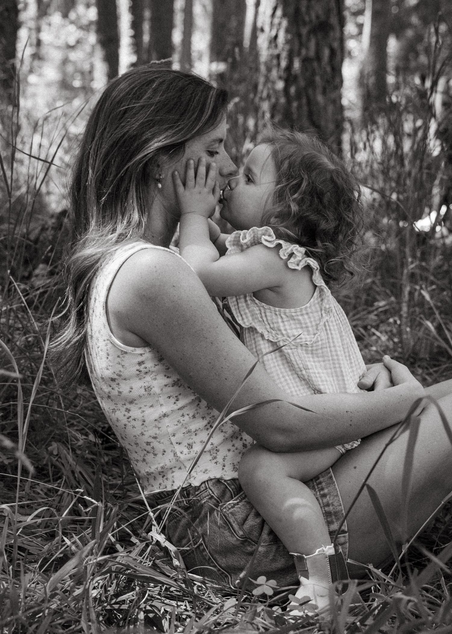 A mother and daughter cuddling in the forest at a motherhood photography session.