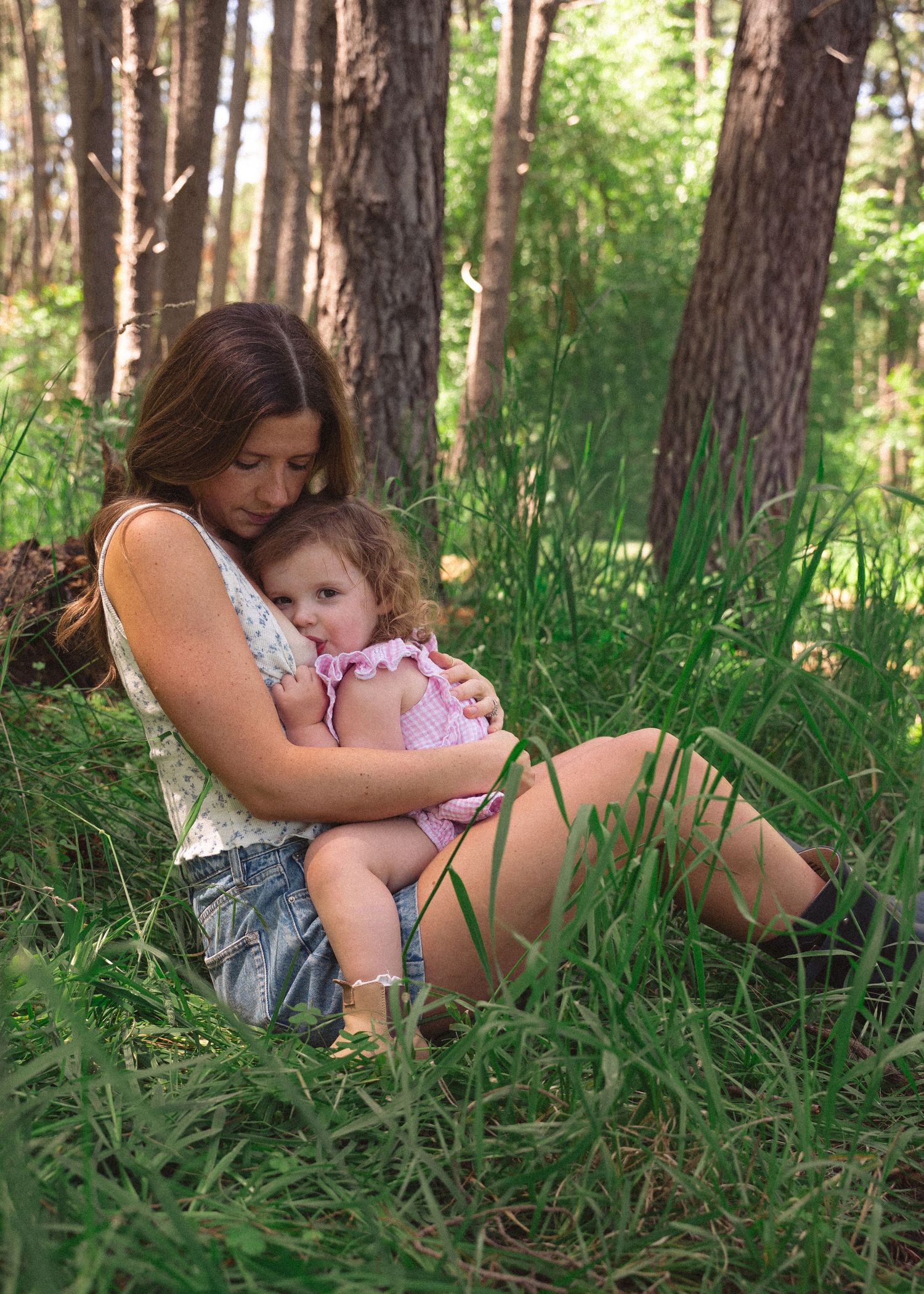 A mother and daughter cuddling in the forest at a motherhood photography session.