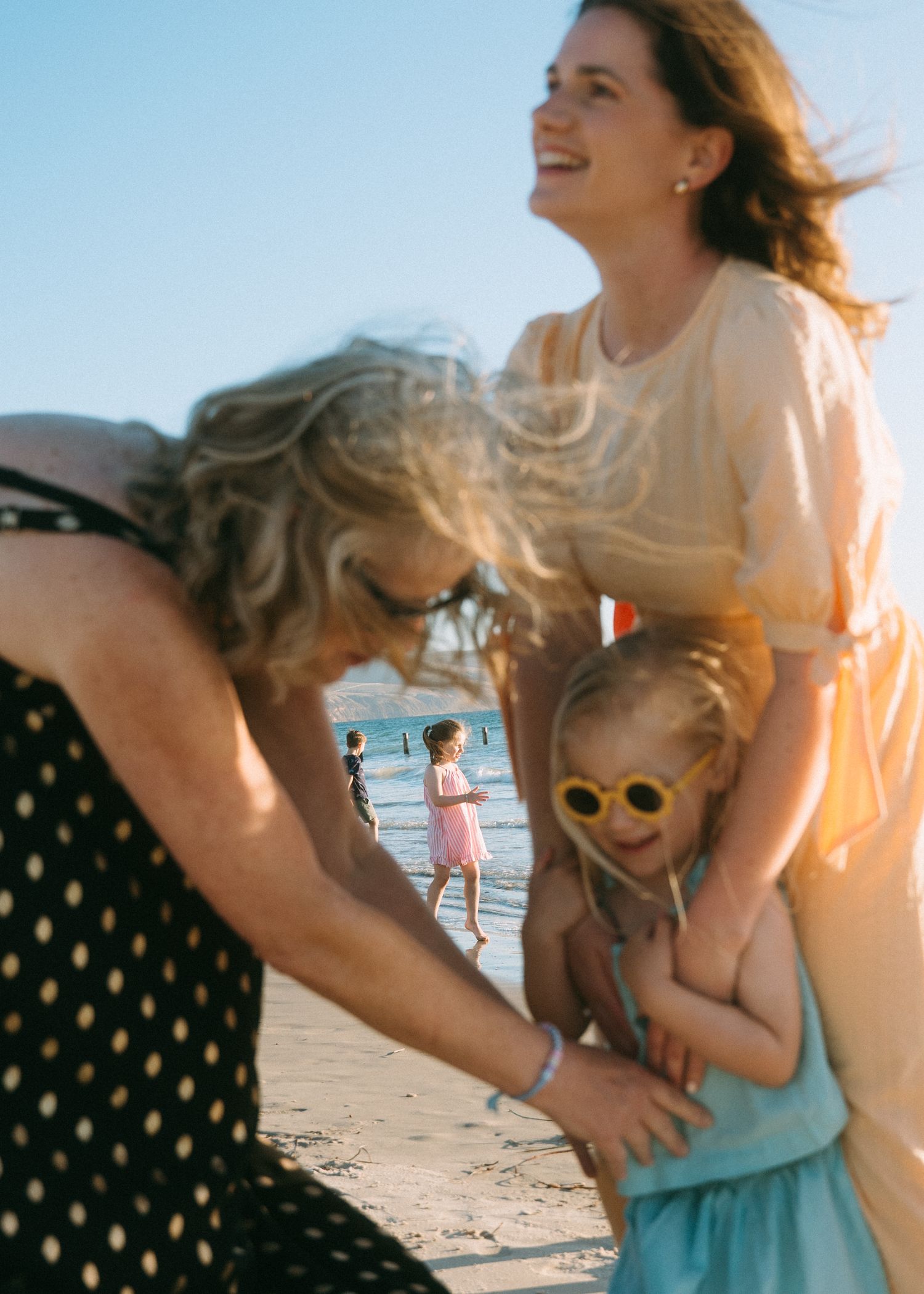 An extended family photoshoot at the beach with the children and grandchildren laughing and having fun together.