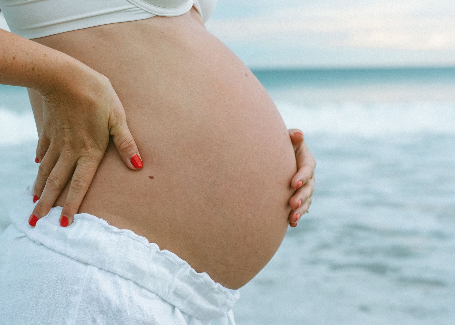 An Adelaide mother at a maternity photoshoot at the beach at golden hour.