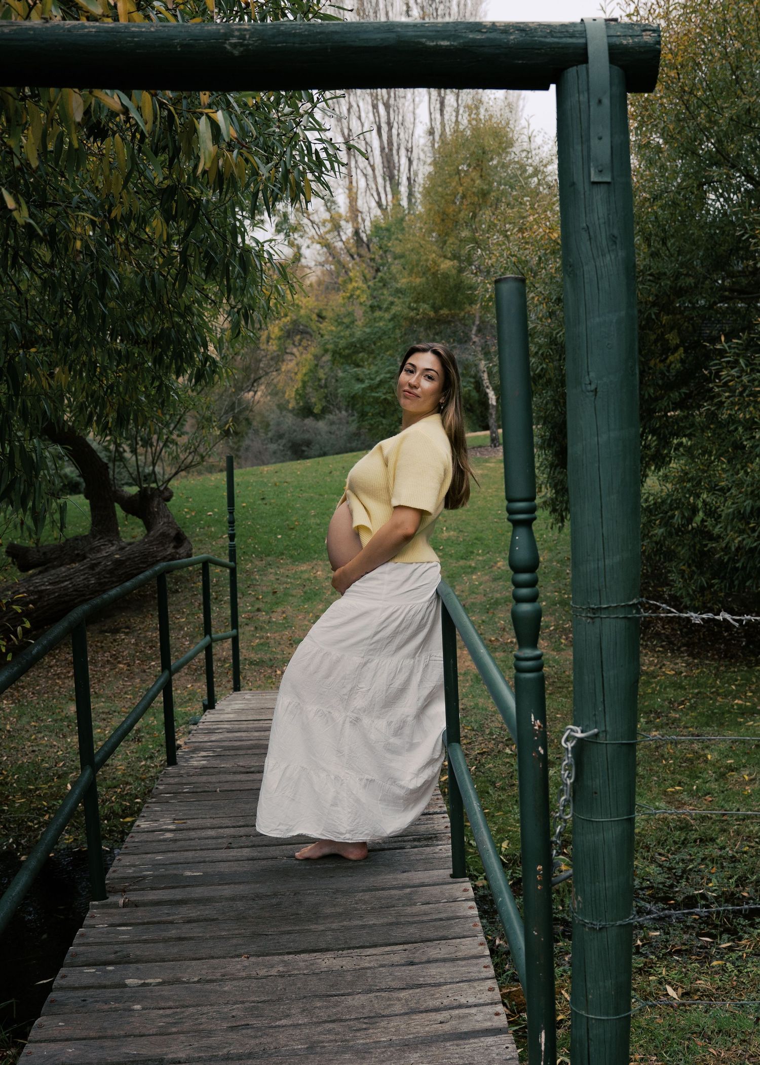 A pregnant woman dancing in a field at the end of her pregnancy in the hills at sunset at a maternity family photography session.
