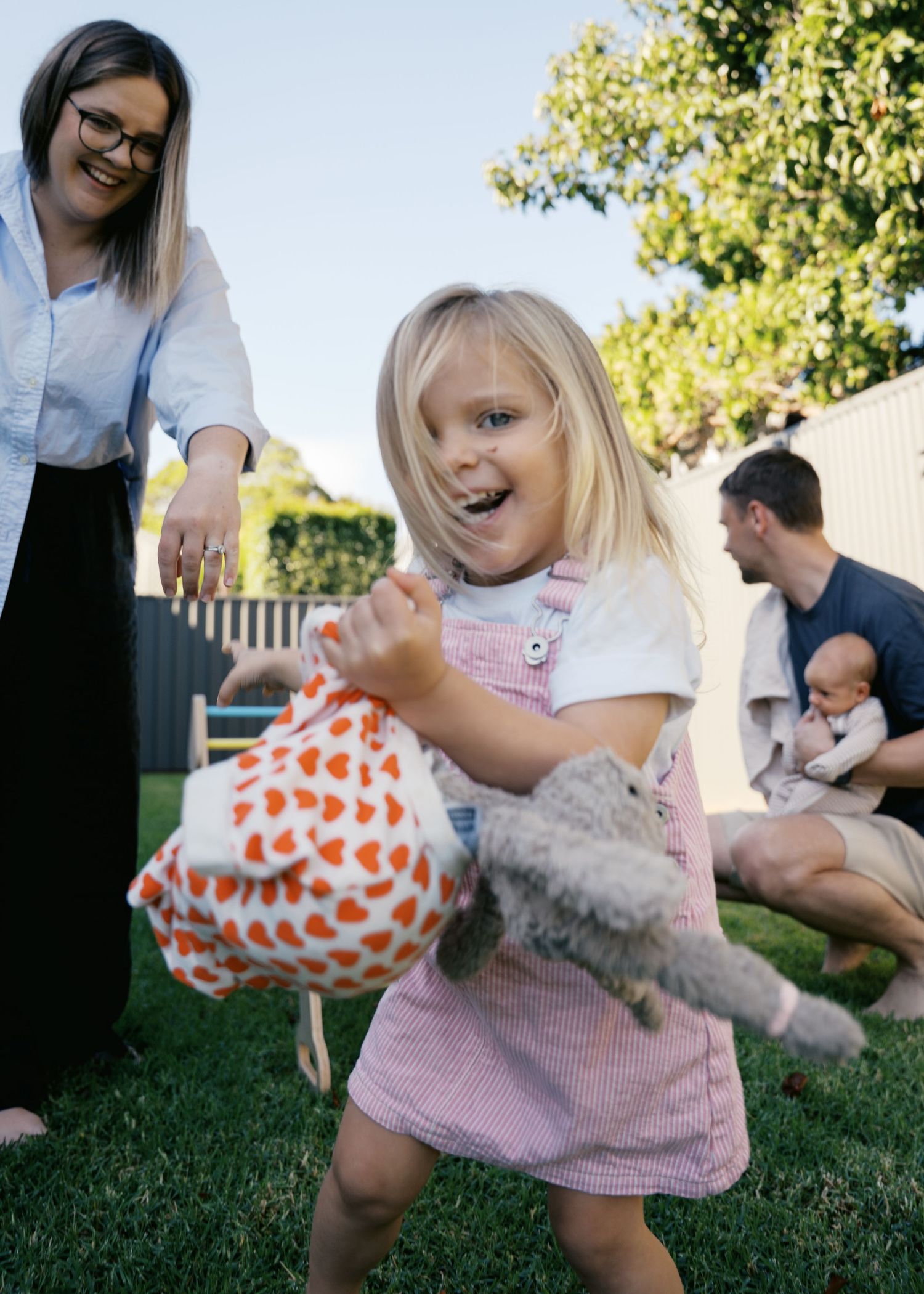 A mother and her toddler daughter playing and laughing at a family newborn photoshoot at their family home.
