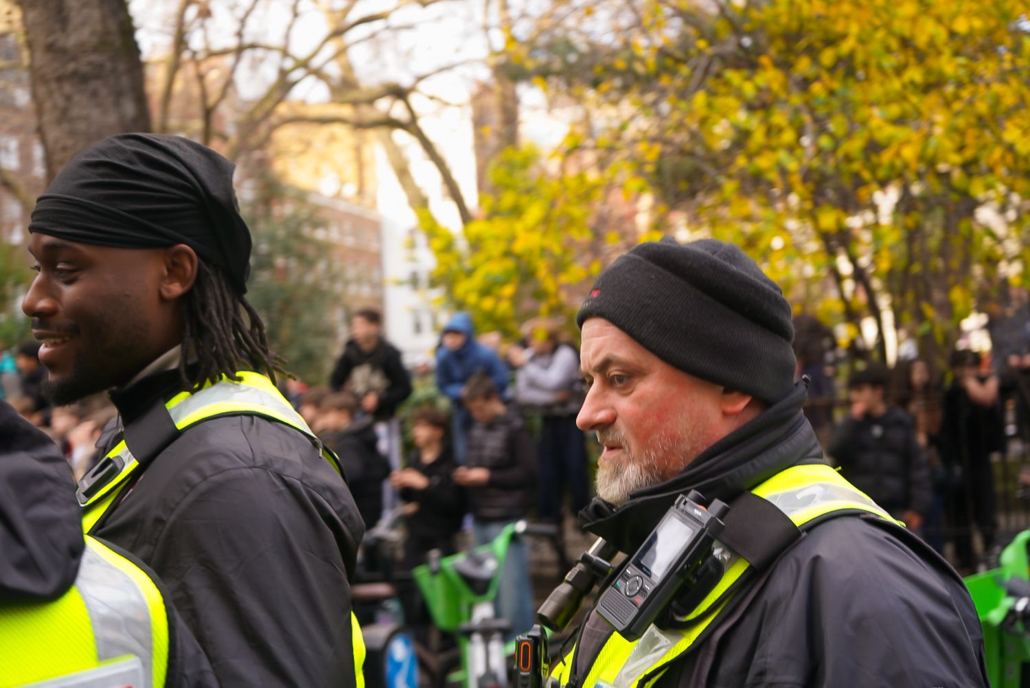 Two security staff wearing yellow high-visibility vests at an outdoor event.
