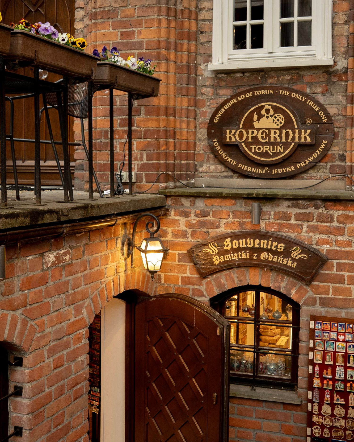 Historic brick building in Torun Poland featuring Kopernik gingerbread shop sign and souvenir store entrance with ornate lamp.
