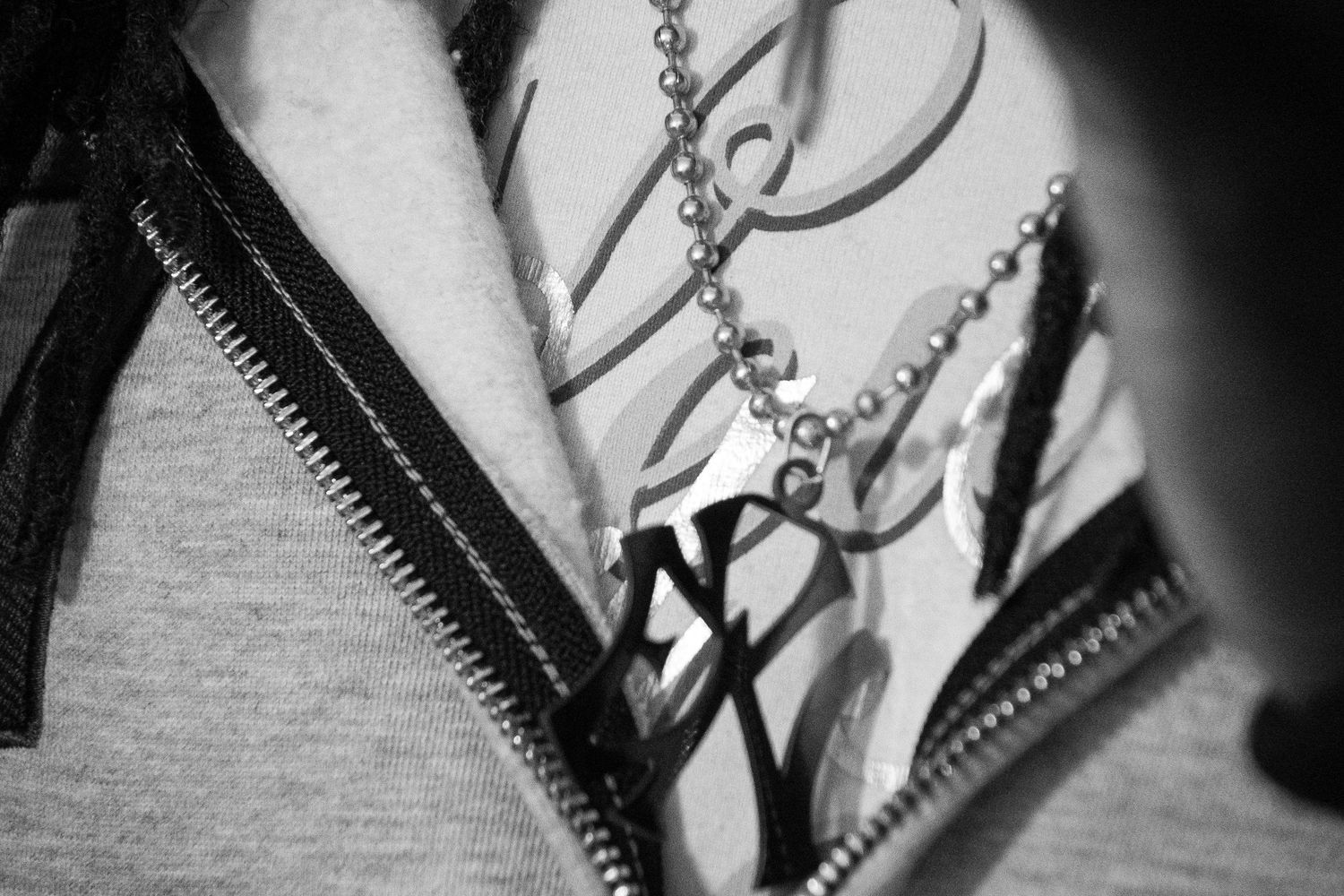 Black and white close-up of a silver star pendant necklace on a graphic print jacket with zipper detail.