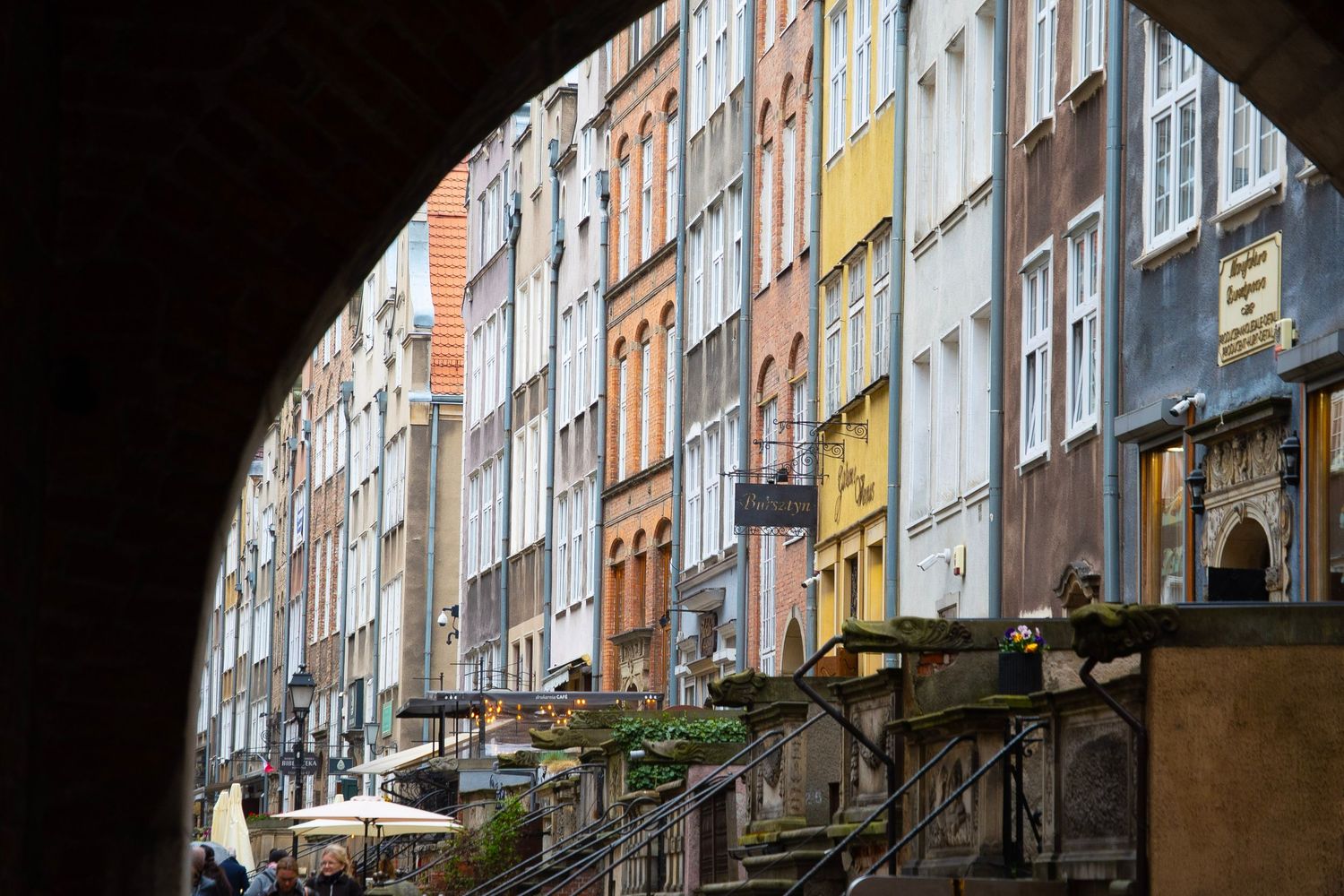 Colorful historic tenement buildings viewed through an archway in Gdansk, Poland's old town district.