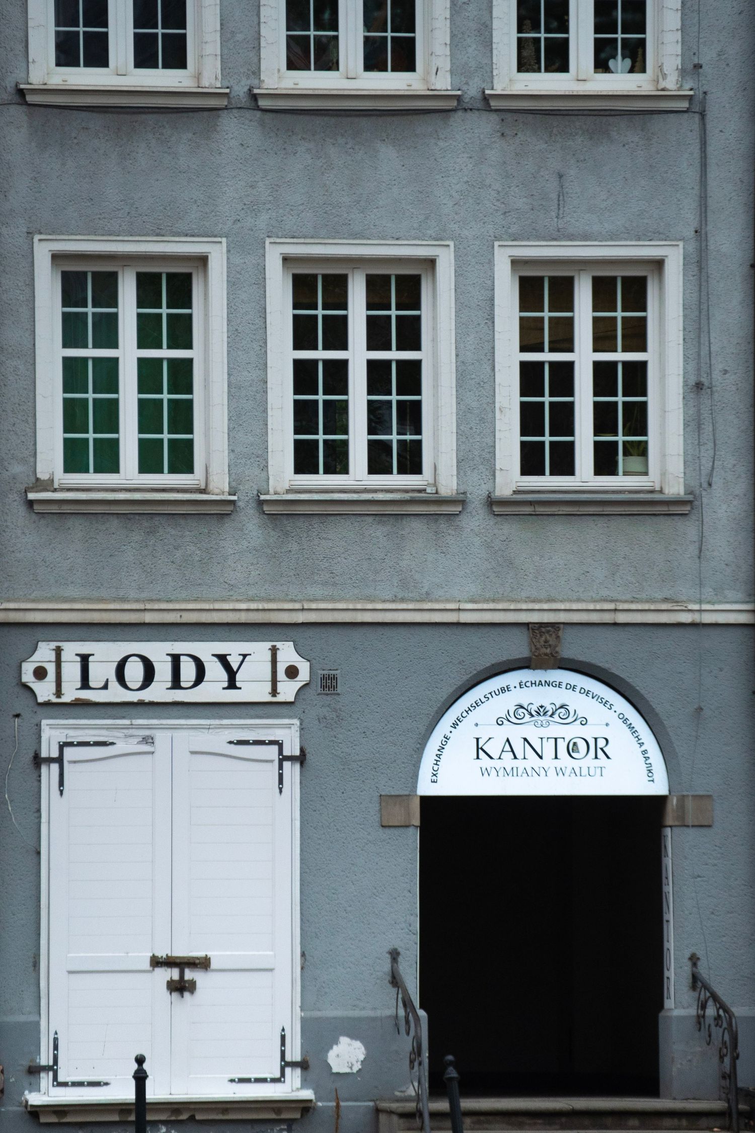 Historic blue building facade in Poland with Lody ice cream shop and Kantor currency exchange entrance.