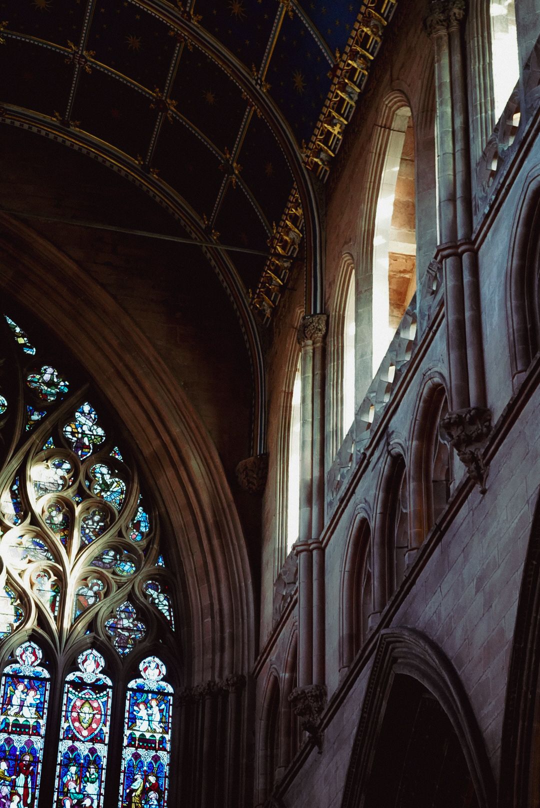 Interior of a Gothic cathedral featuring ornate stained glass windows and arched stone walls.
