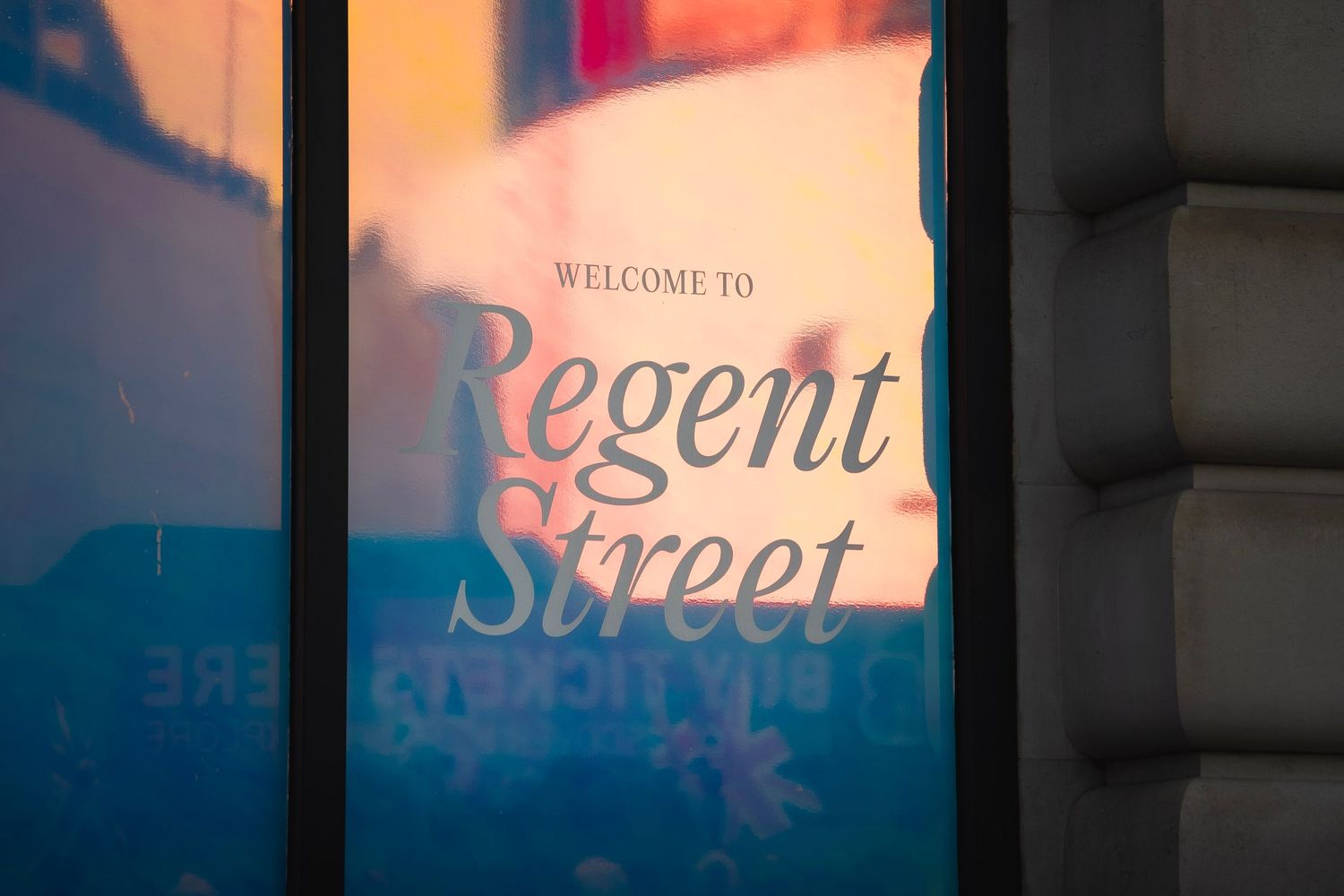 Welcome to Regent Street sign displayed on a window with warm golden light reflections in London.