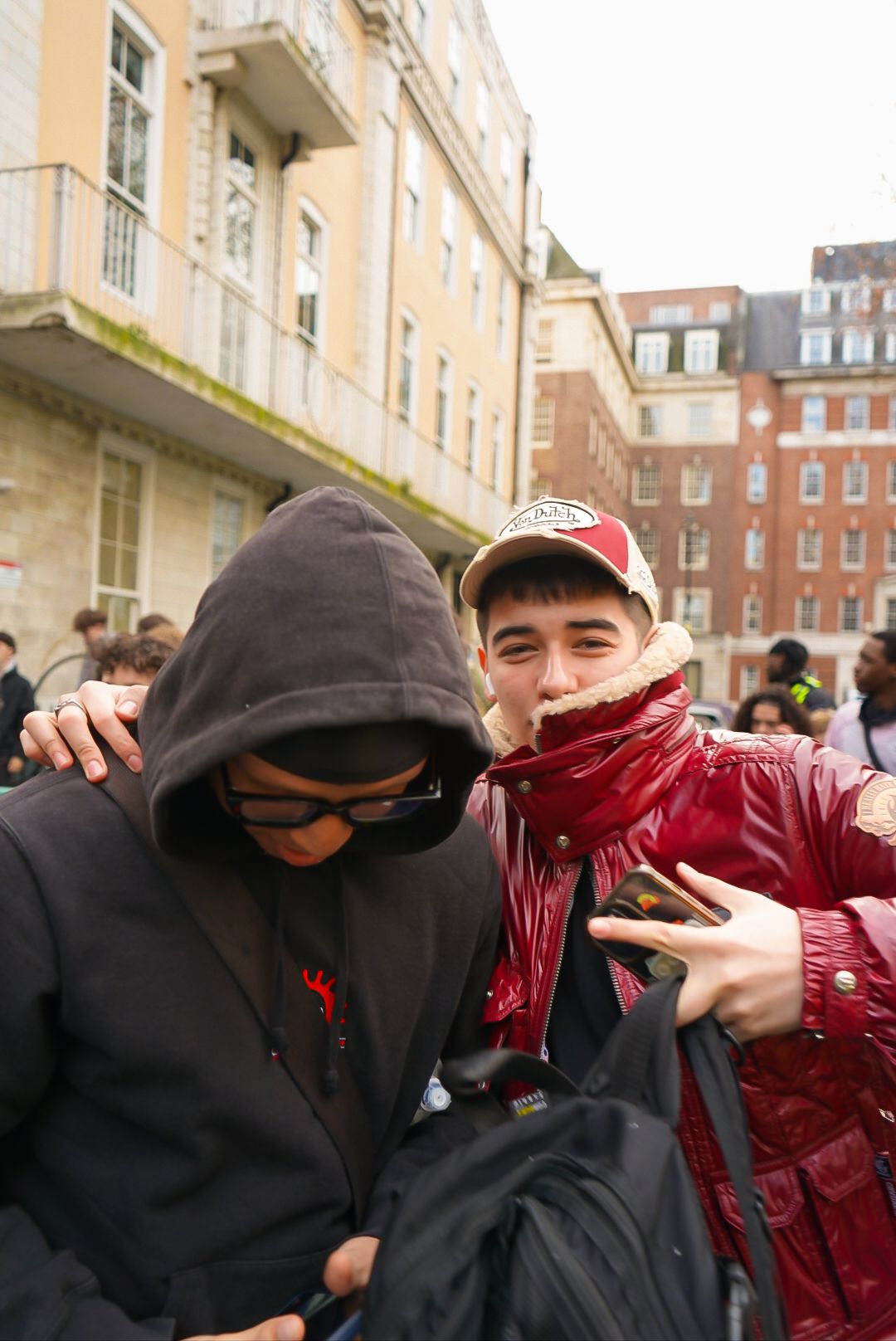 Two young men posing together outdoors in an urban setting in London.