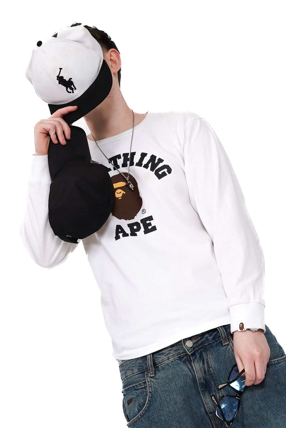 Male model in white BAPE long sleeve shirt covering face with black cap, holding sunglasses.