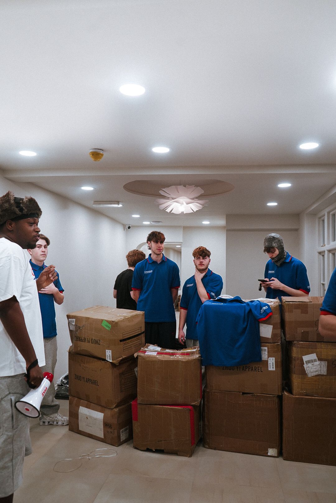 Staff in blue polo shirts organizing cardboard boxes in a bright white room.