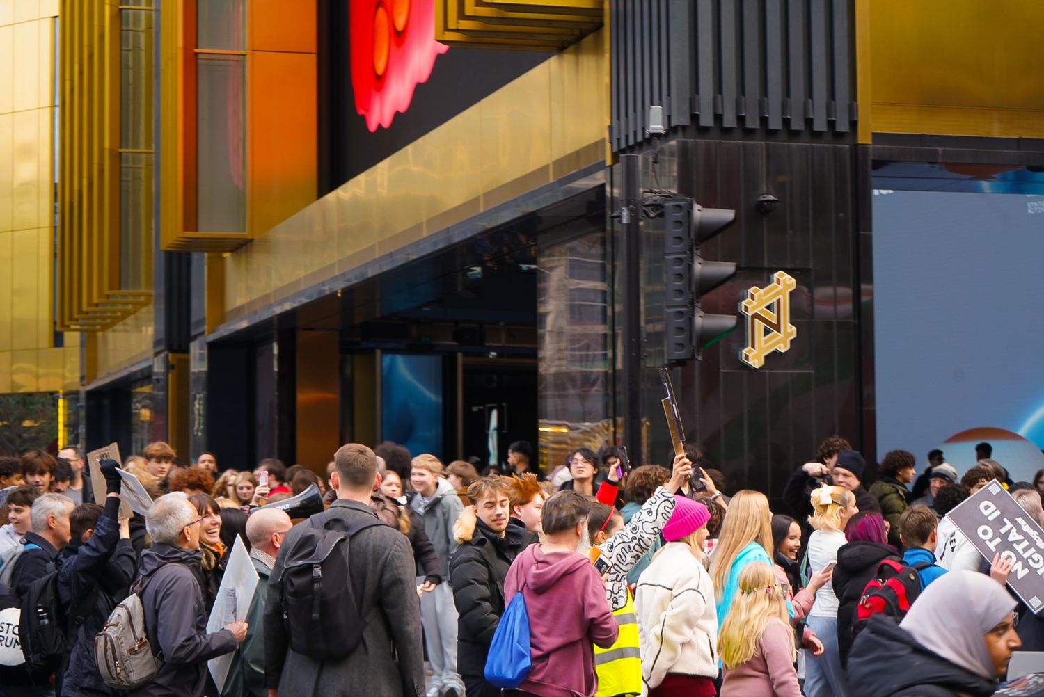 Large crowd of people gathered outside a modern retail store entrance.