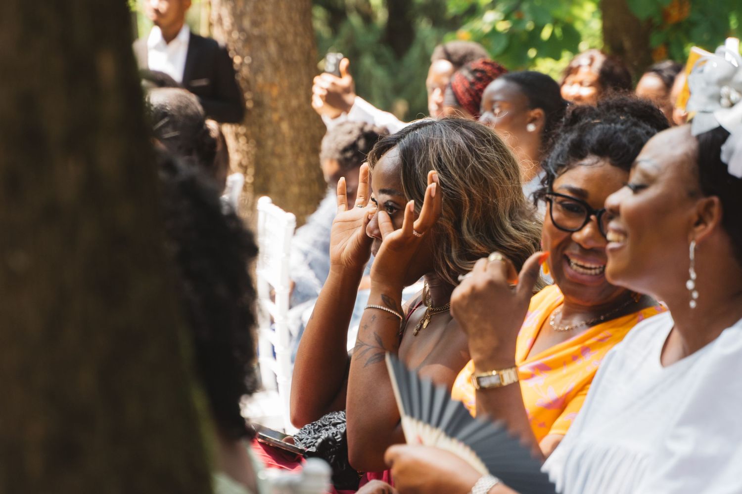 Wedding guests enjoying outdoor celebration under trees.