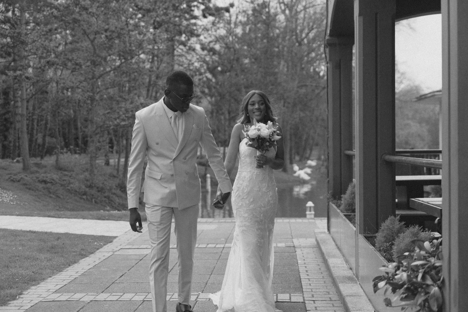 Newlyweds walk together along an outdoor pathway during their wedding.