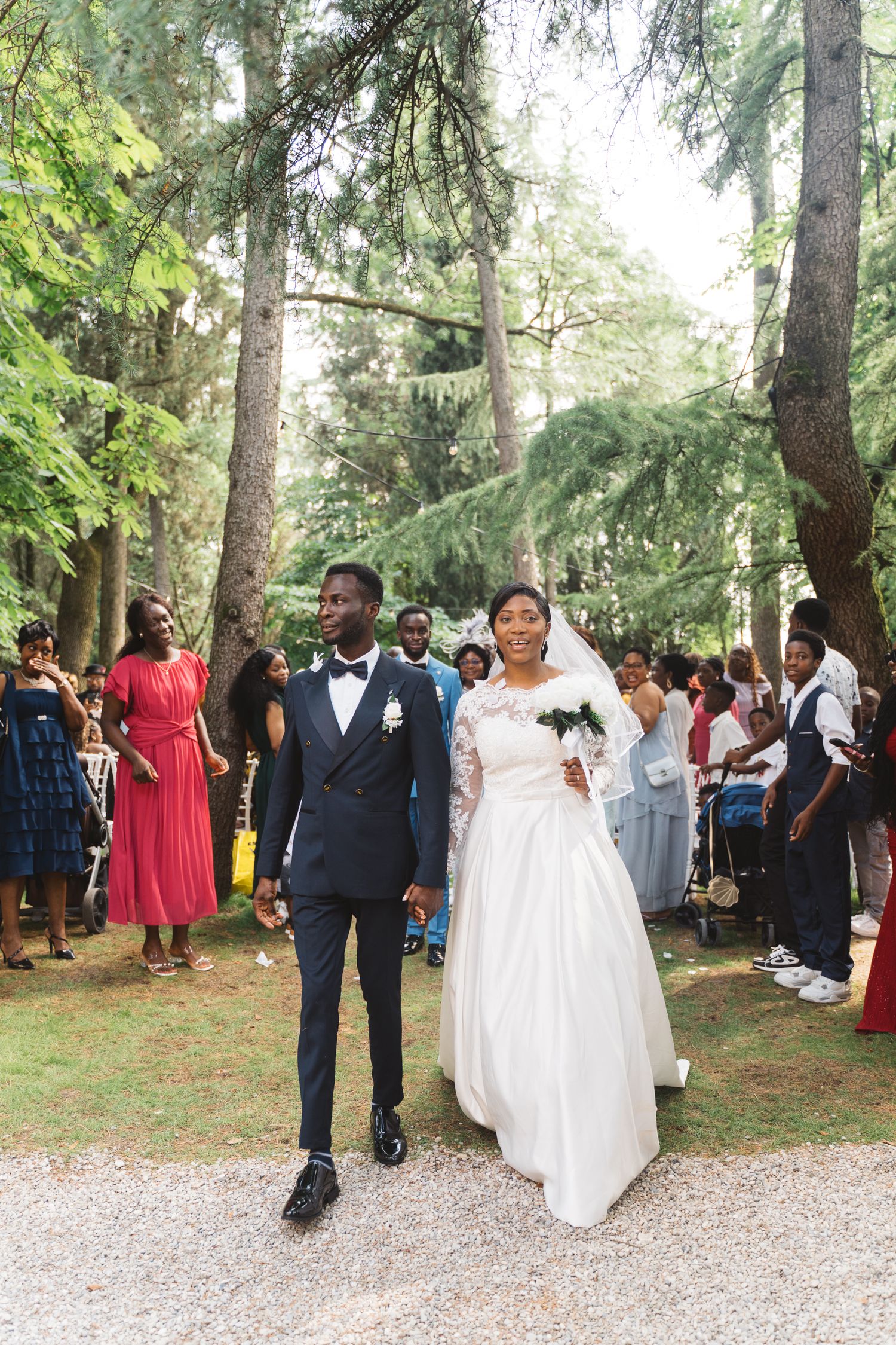 A couple walks down a forest path after their wedding ceremony.