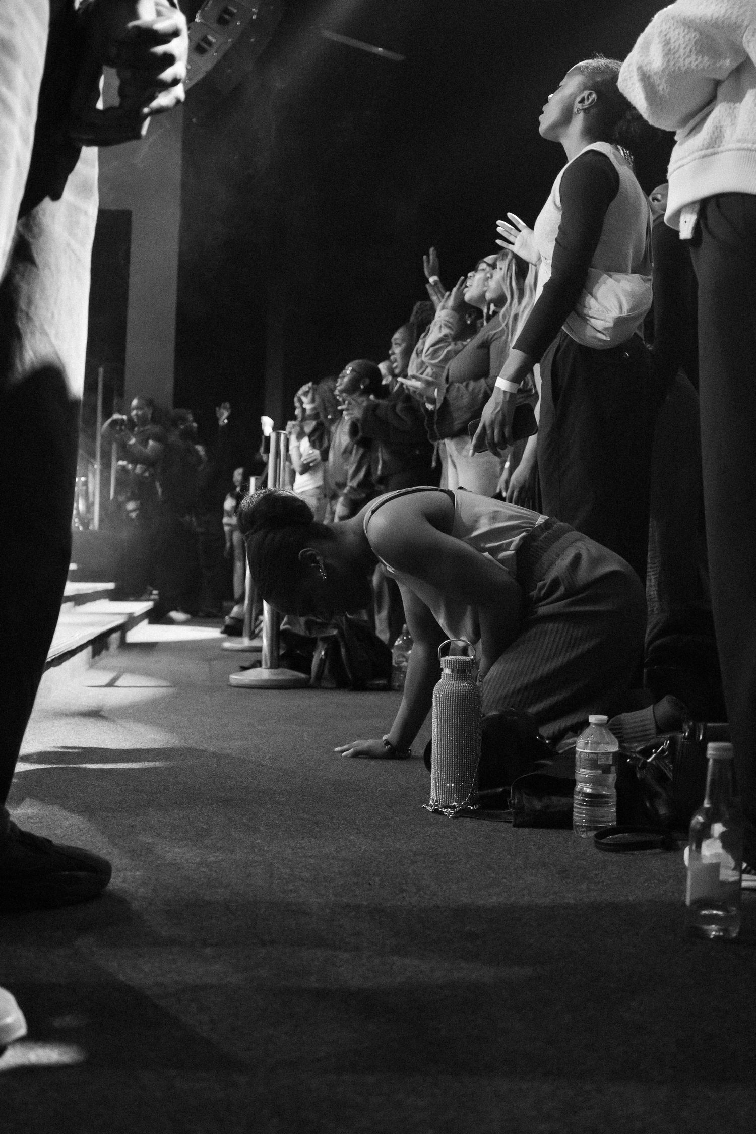Black and white image showing silhouettes of people seated in a row.