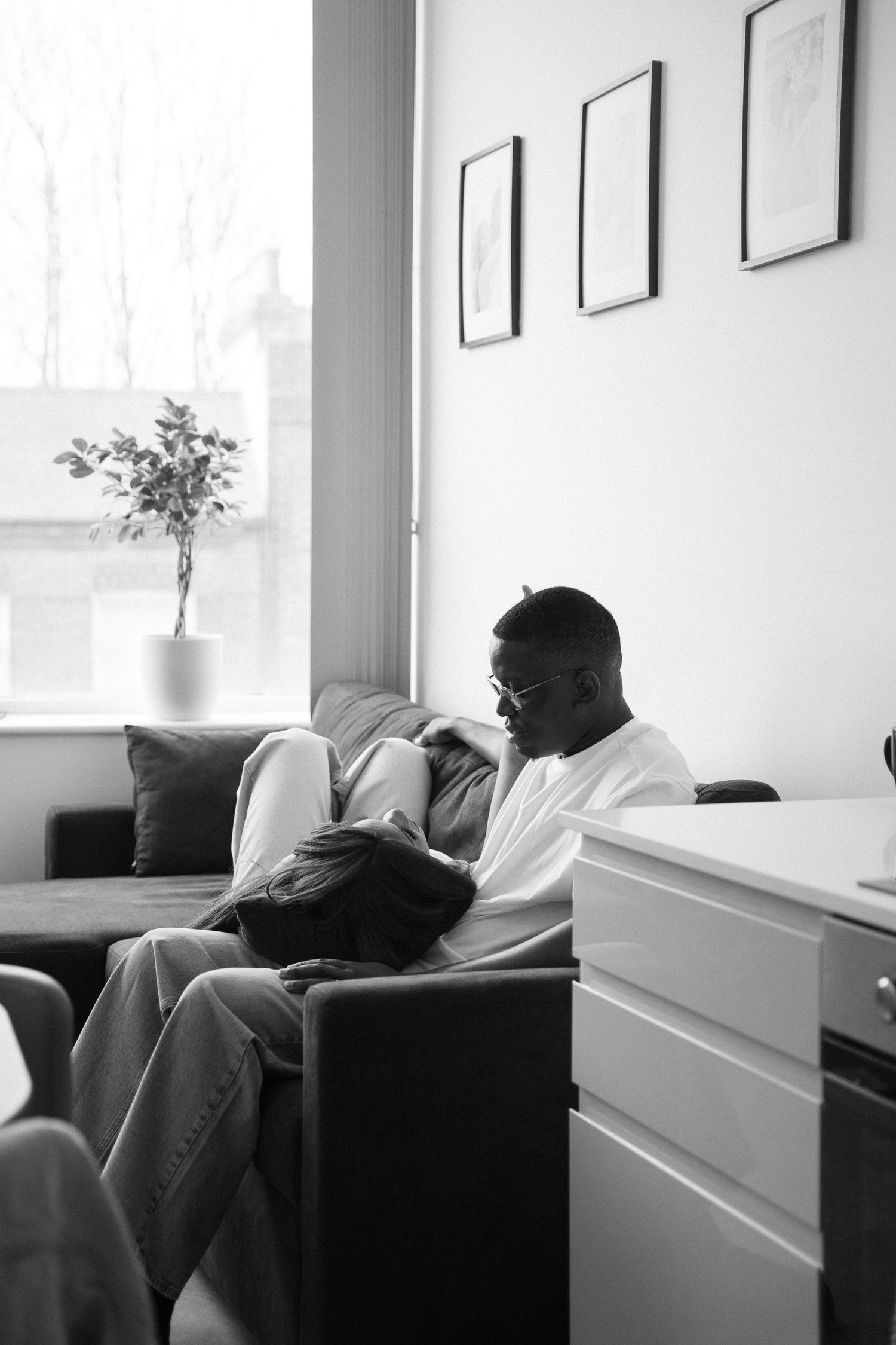 Black and white photo of someone relaxing on a couch in a minimalist room.