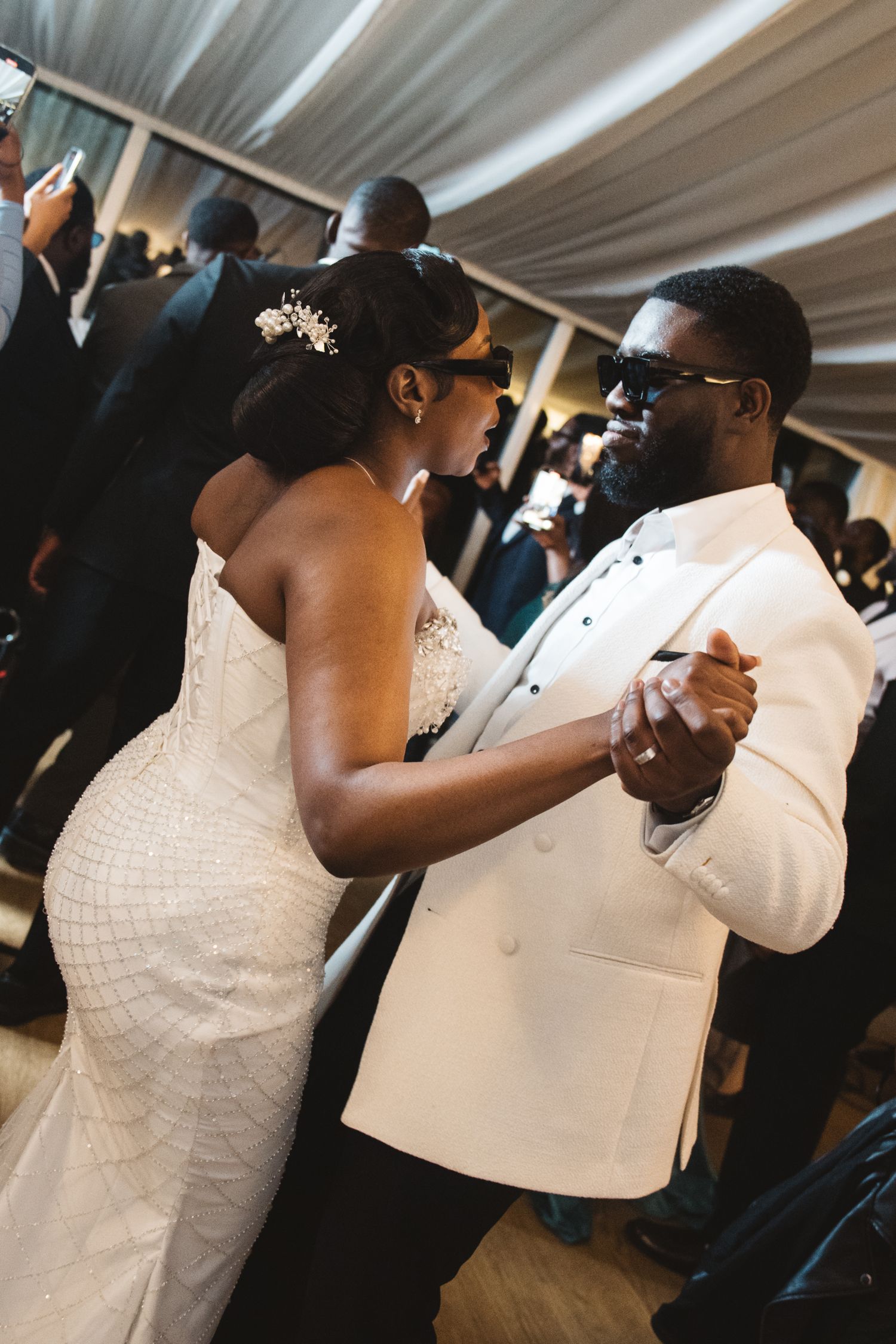 Couple shares their first dance at wedding reception under white tent.