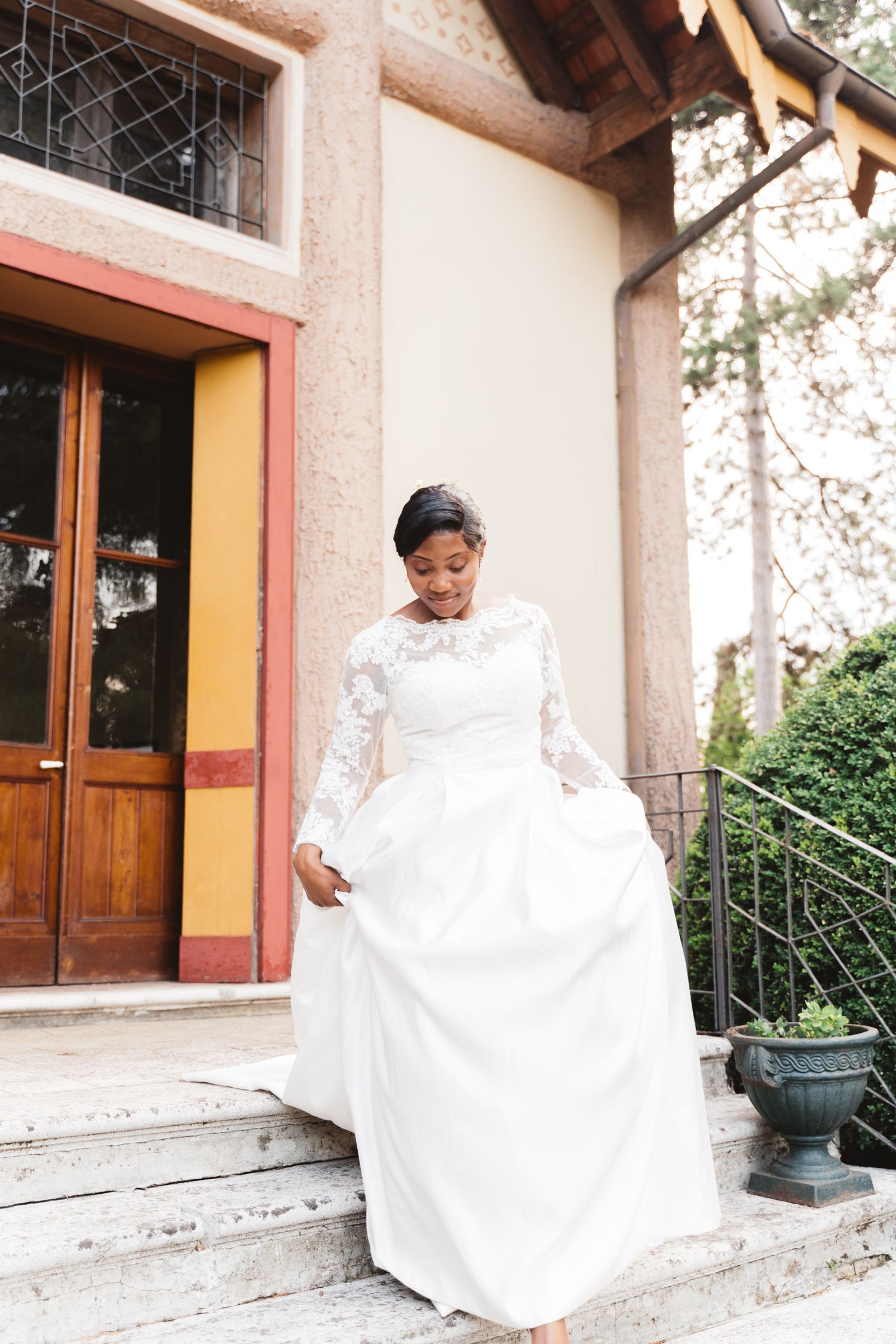 Elegant white wedding dress flowing on stone steps of historic building.
