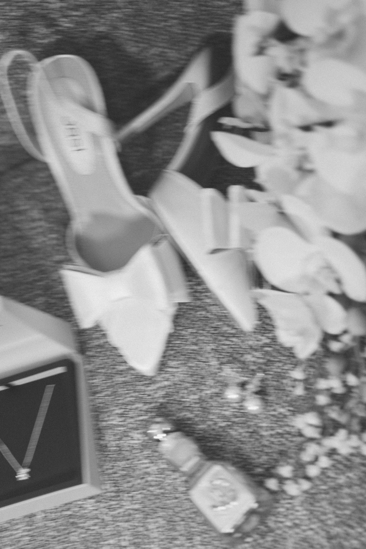 Wedding shoes and accessories arranged on a textured dark surface.