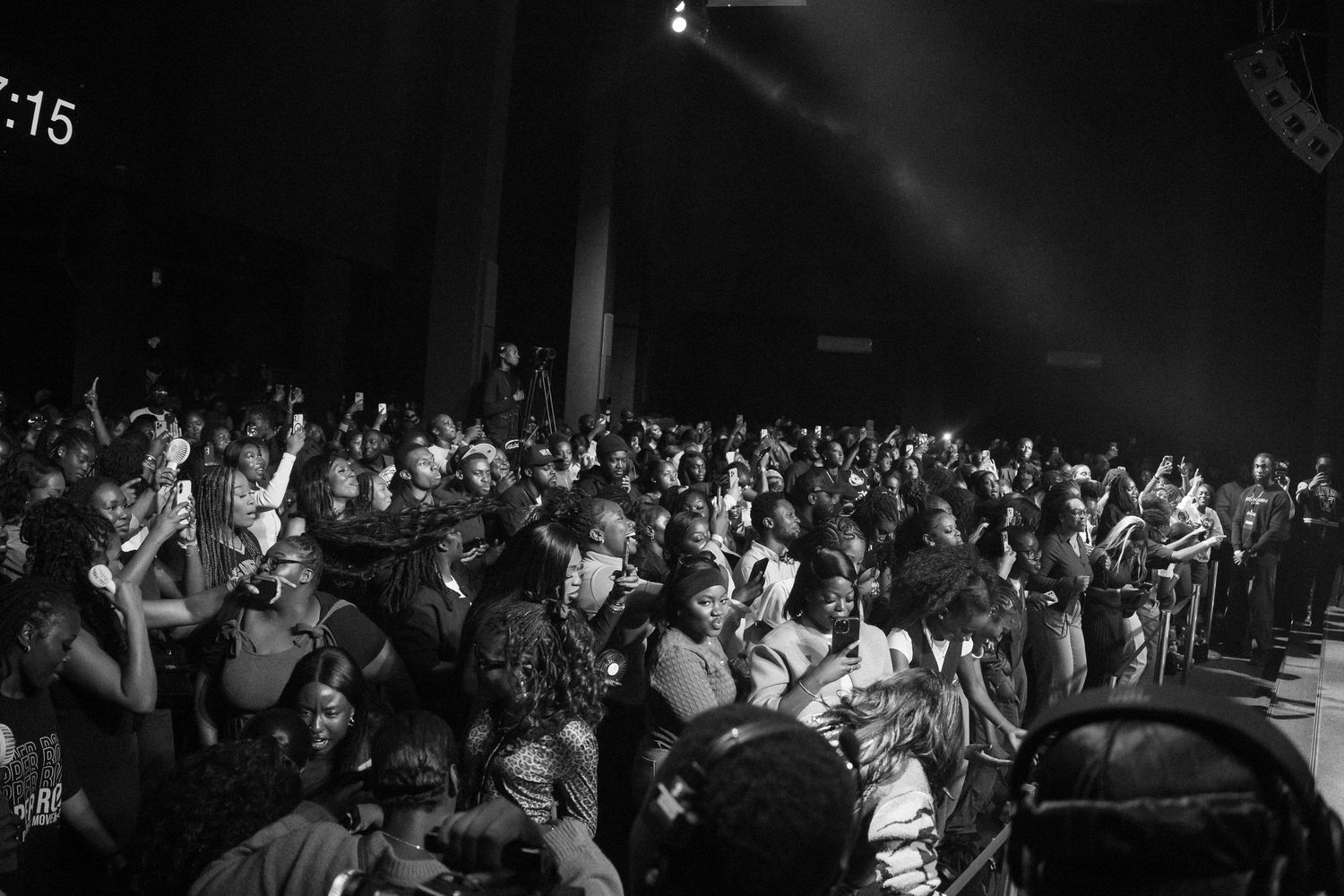 Concert crowd silhouette with dramatic lighting at a large indoor venue.