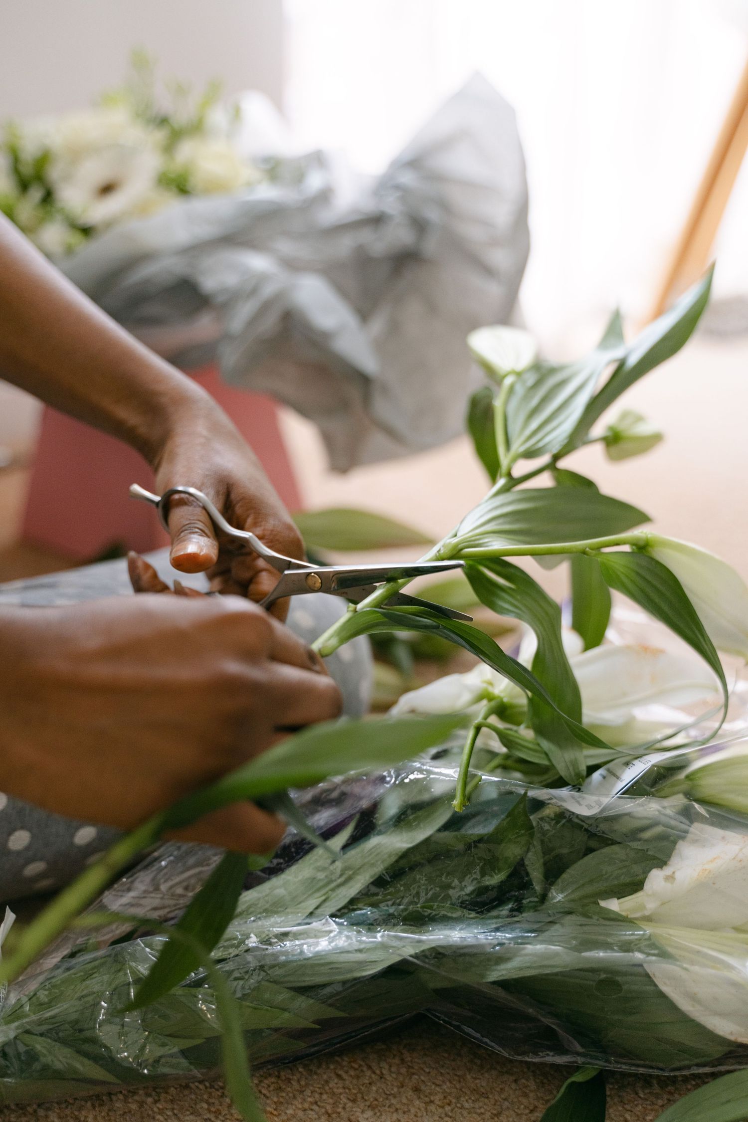 Hands arranging fresh green foliage and white flowers for wedding decor.