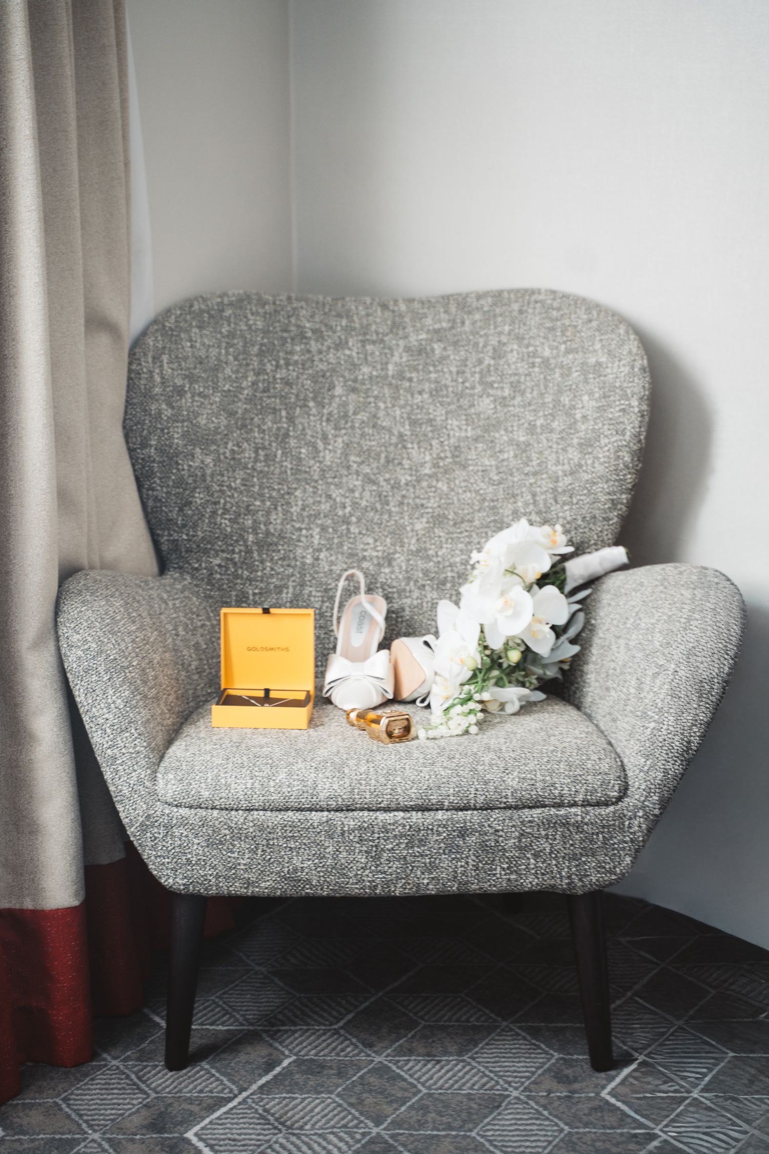 A modern grey loveseat with white flowers and a yellow clutch purse displayed.
