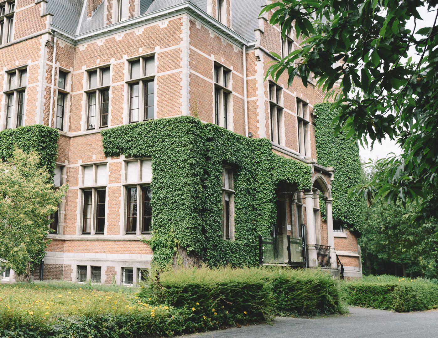 Historic brick building exterior with ivy-covered walls and arched windows.