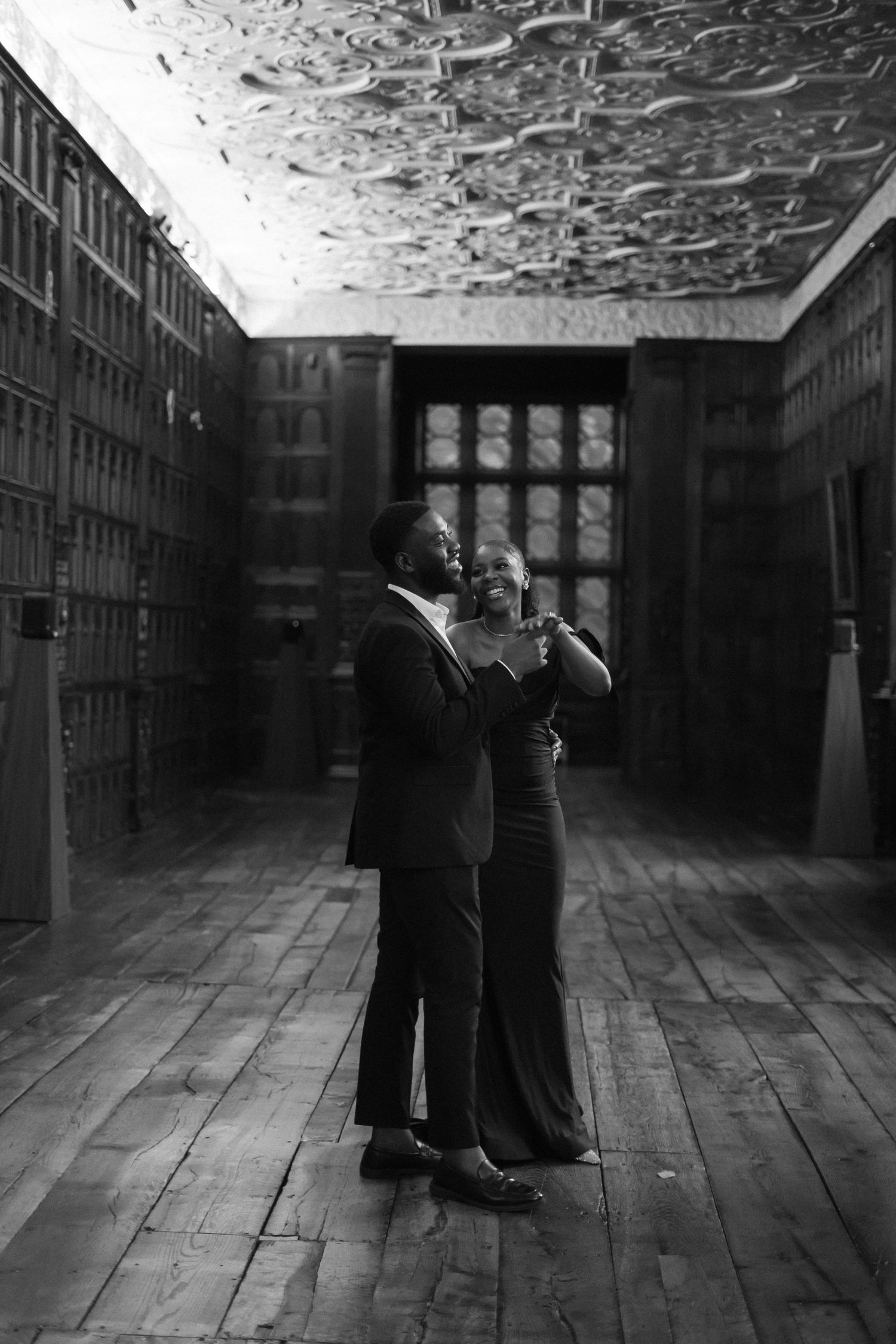 Couple in formal wear dance in an atmospheric old hallway with wooden floors.