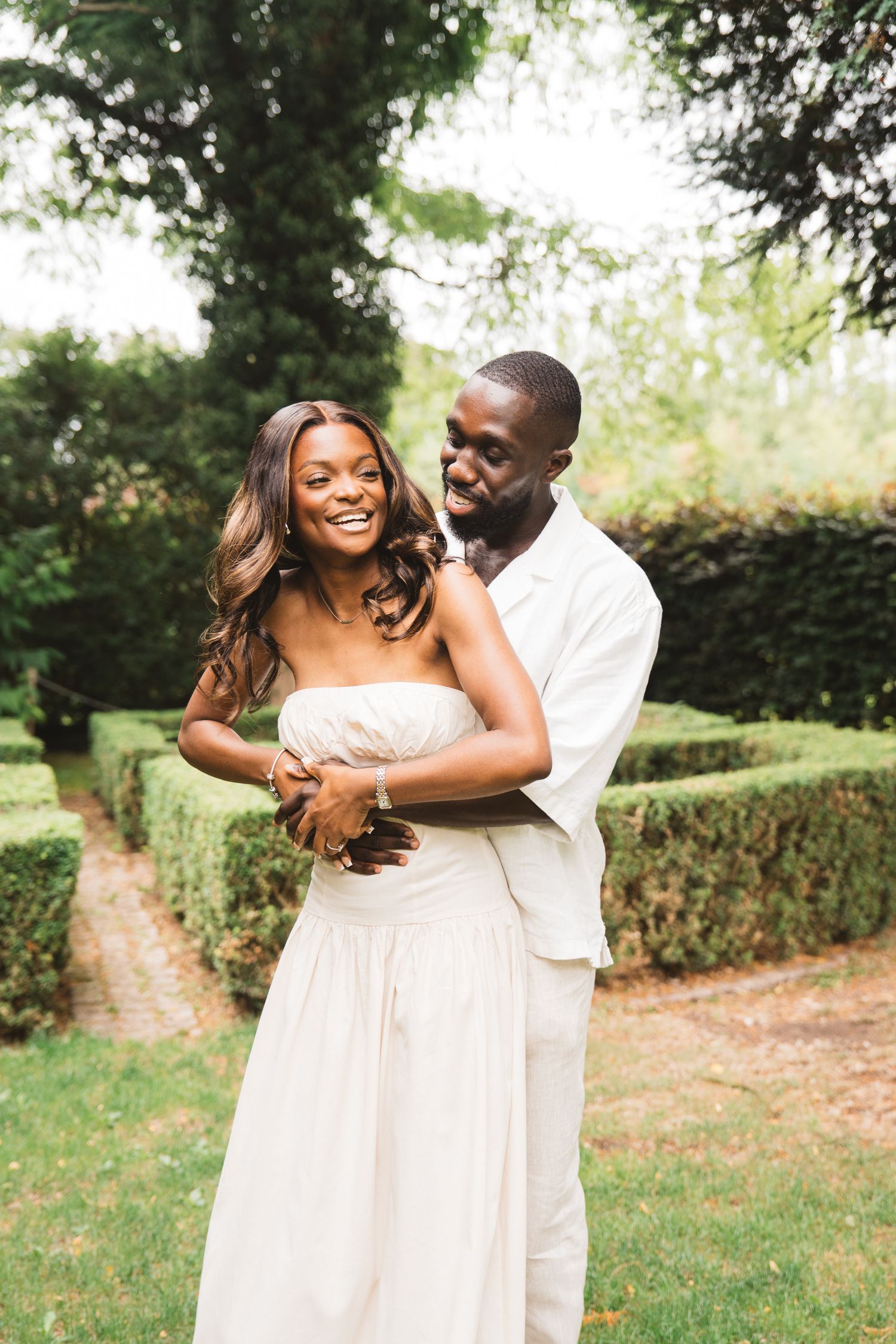 Romantic couple in white attire sharing joyful moments in a lush garden setting.