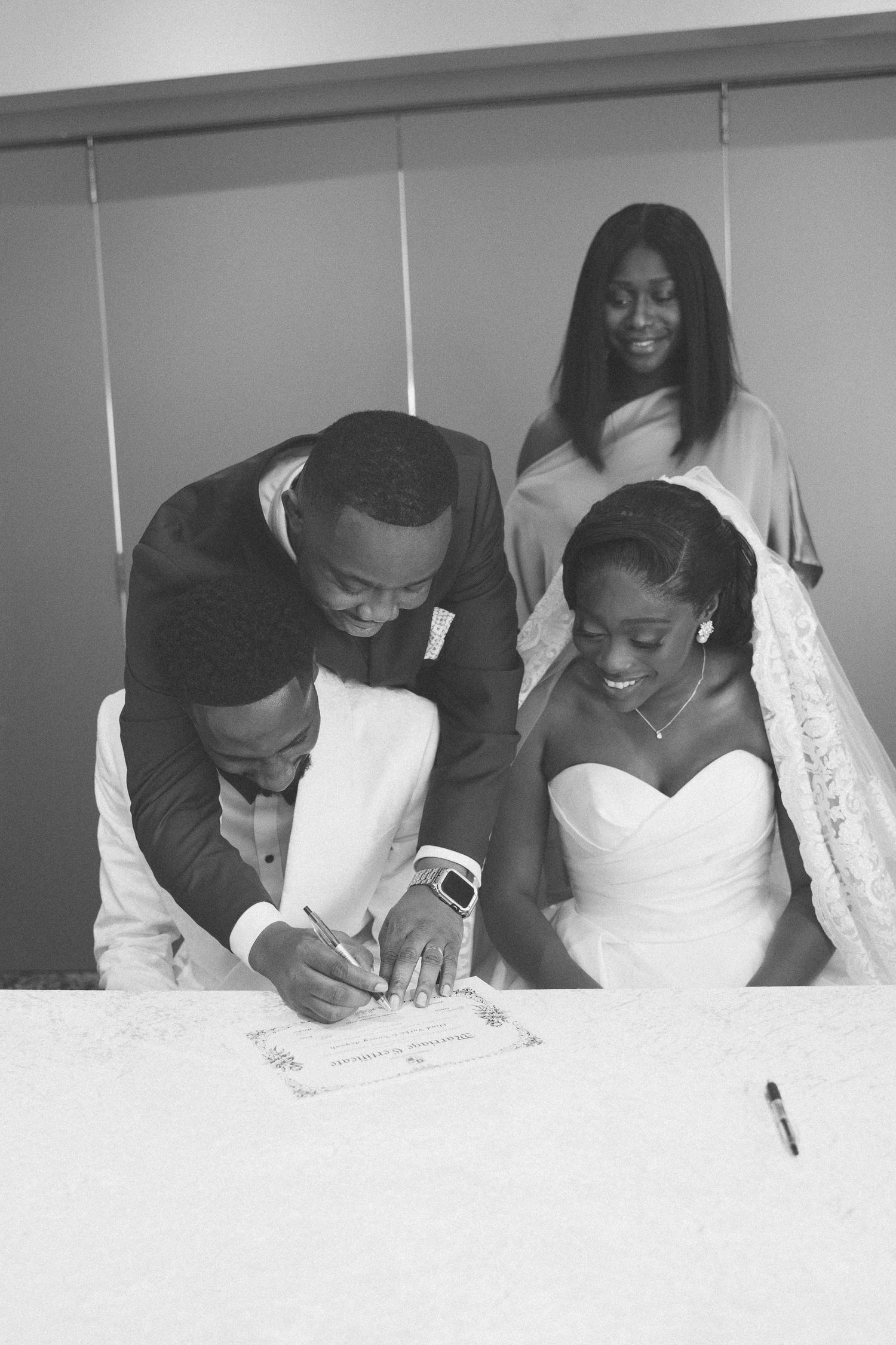 Wedding couple signing official marriage documents in black and white.