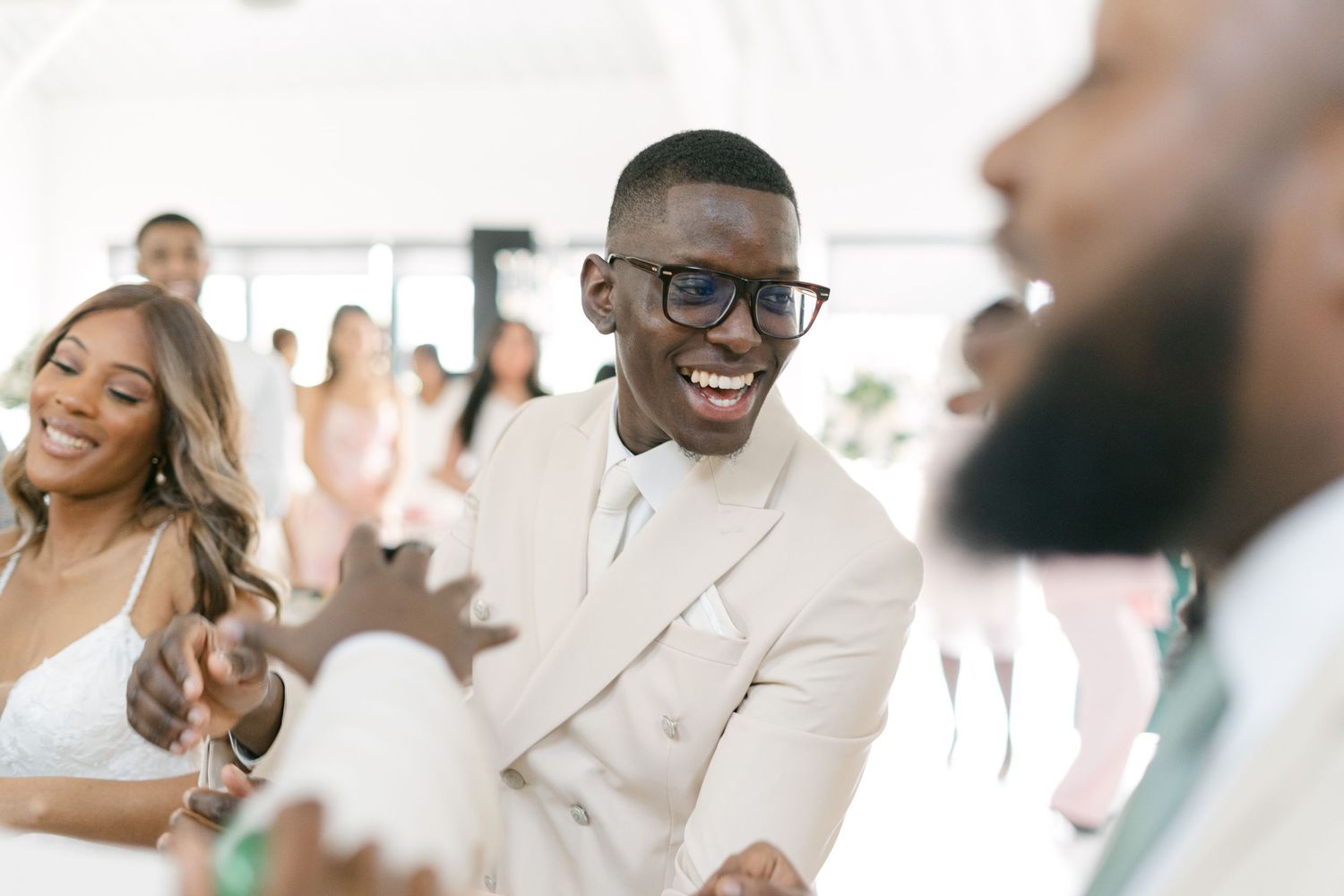 Wedding party members share joyful moments in cream-colored attire.