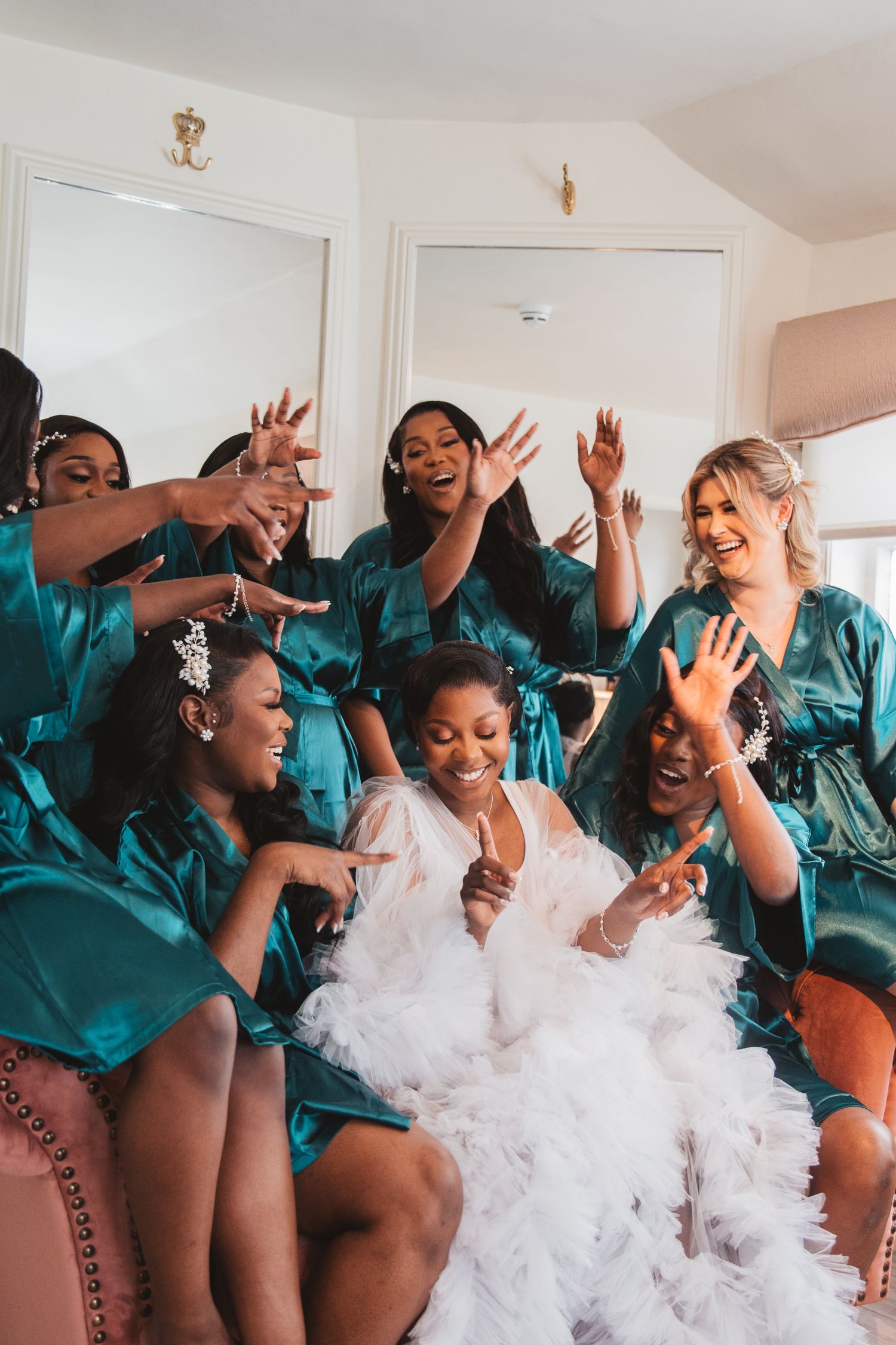 Wedding party in teal robes celebrating joyfully together during pre-ceremony preparations.