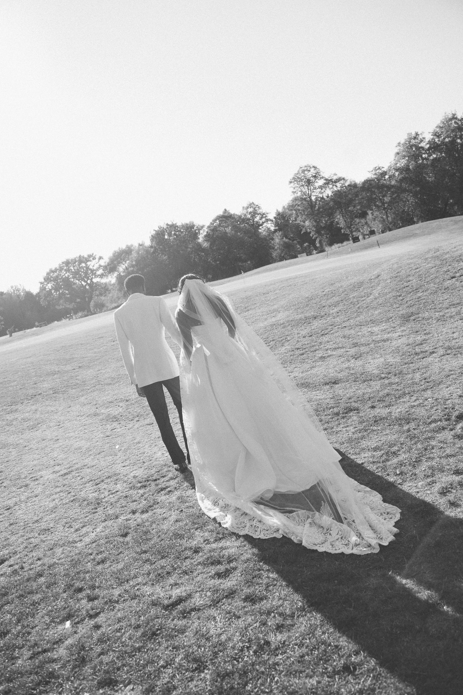 Artistic black and white shots of couple walking across a sunlit hillside.