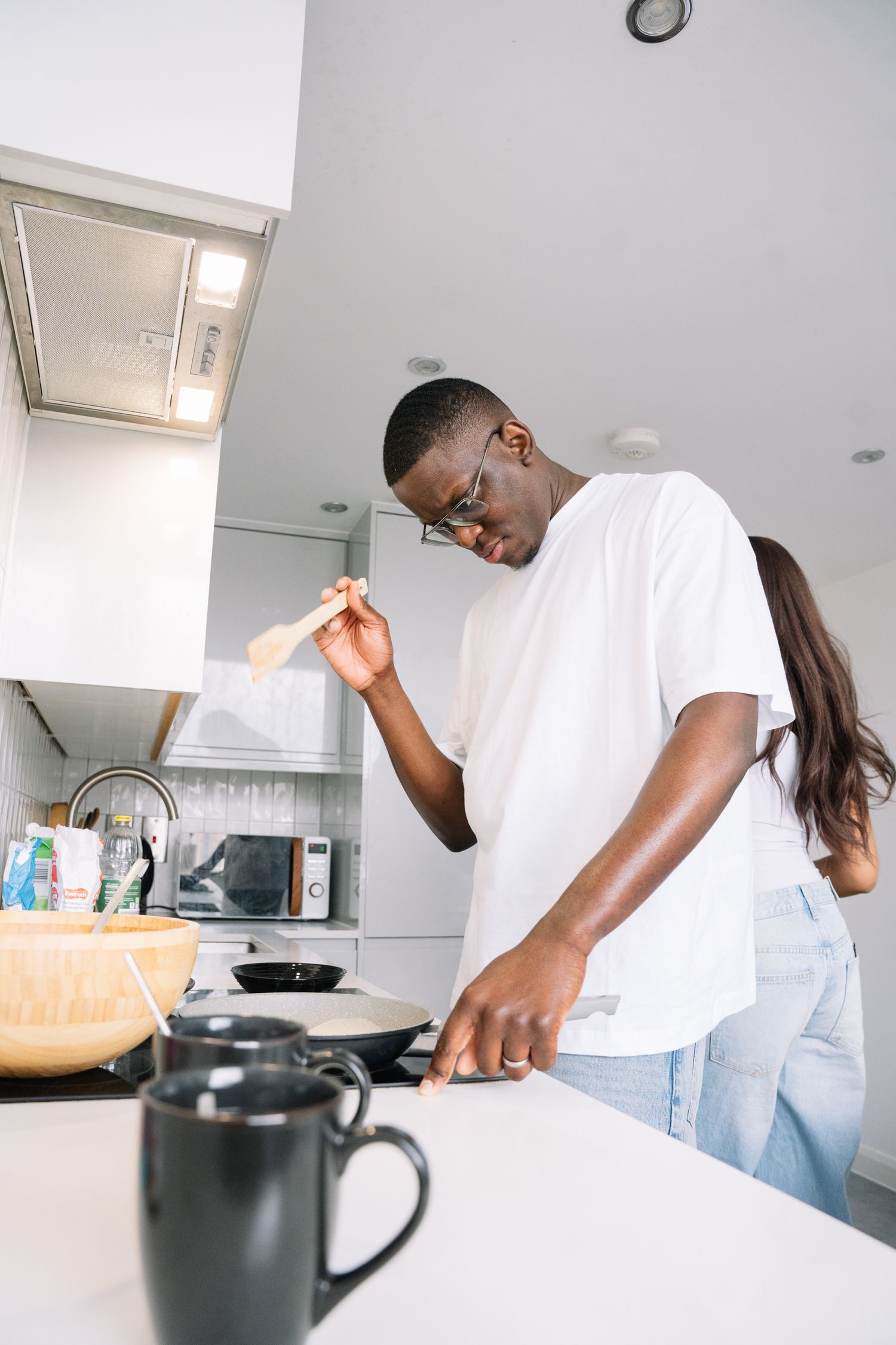 Person in white shirt preparing coffee or tea in a bright modern kitchen.