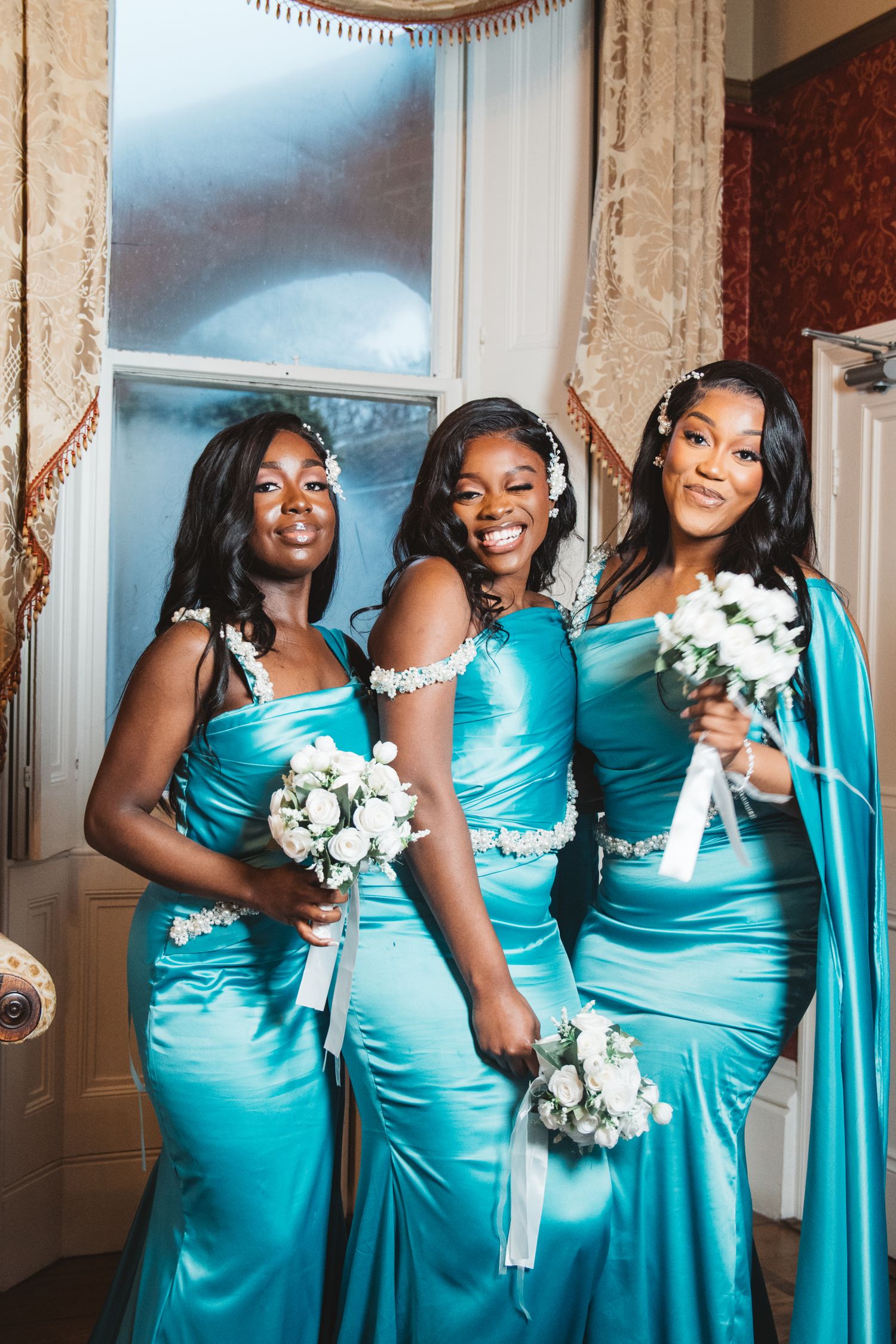 Bridesmaids in matching turquoise dresses pose with white bouquets.