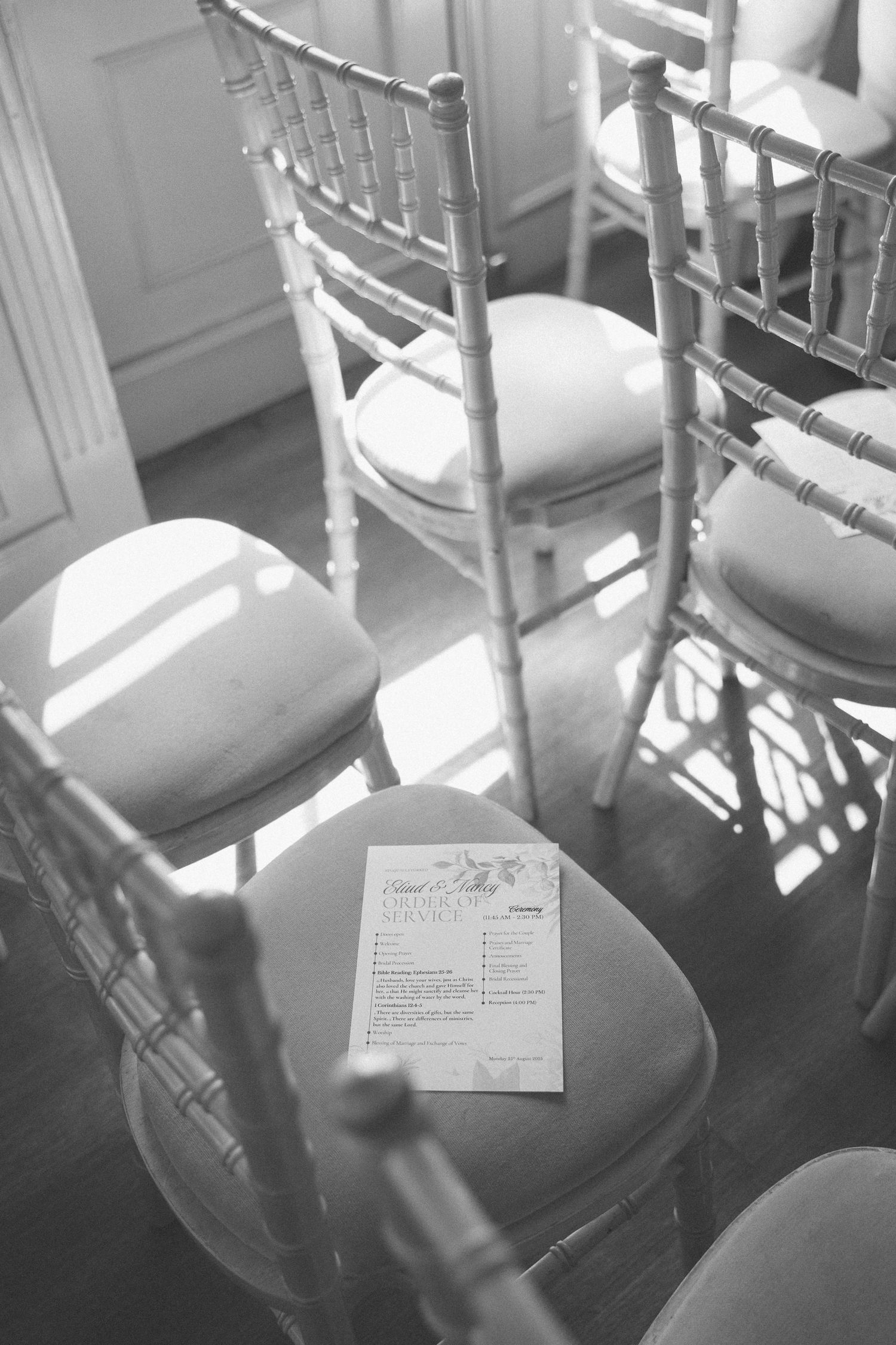 Elegant white Chiavari chairs arranged in rows with a small card placed on the cushioned seat.