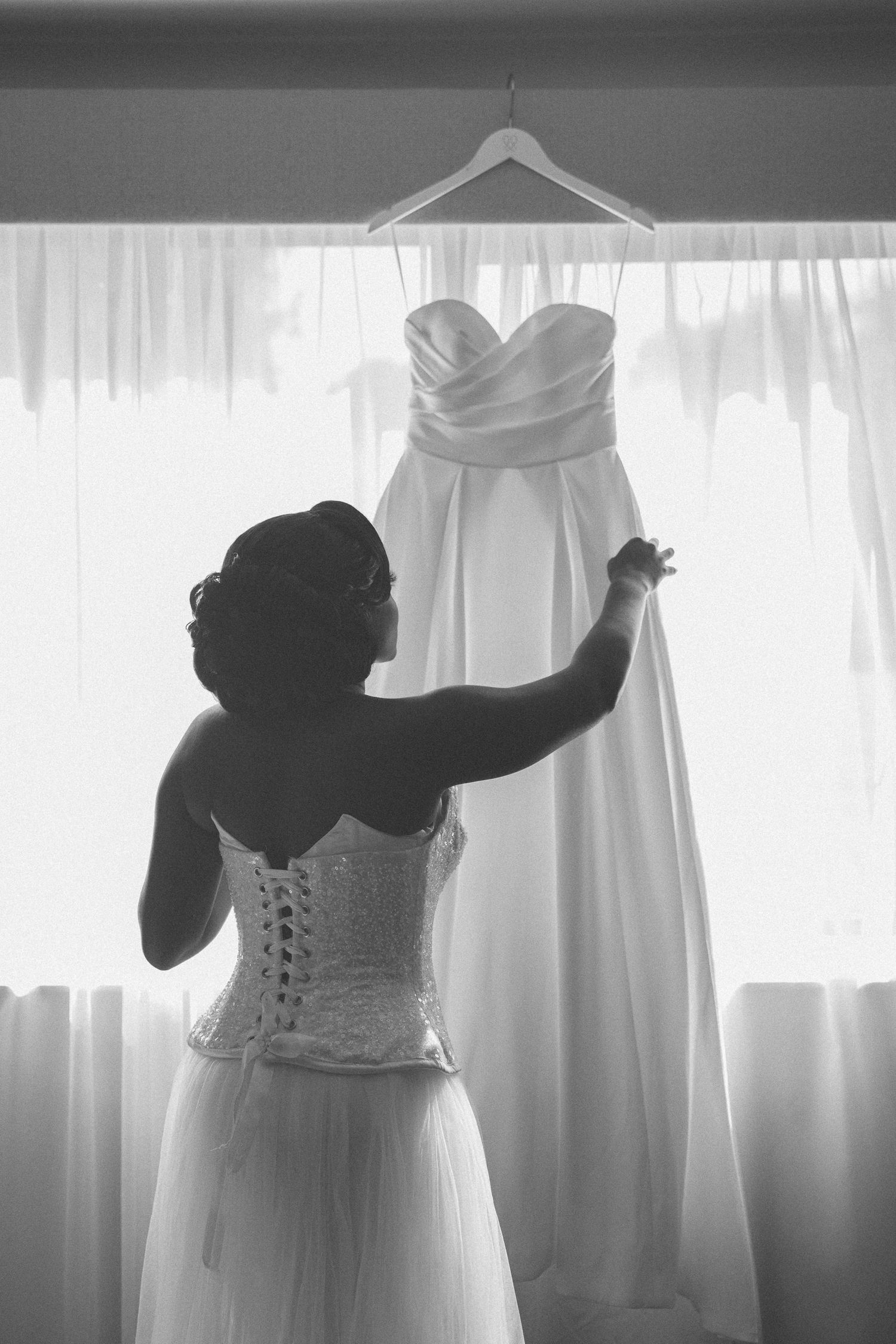 Wedding dress details shown through silhouettes against bright window light.