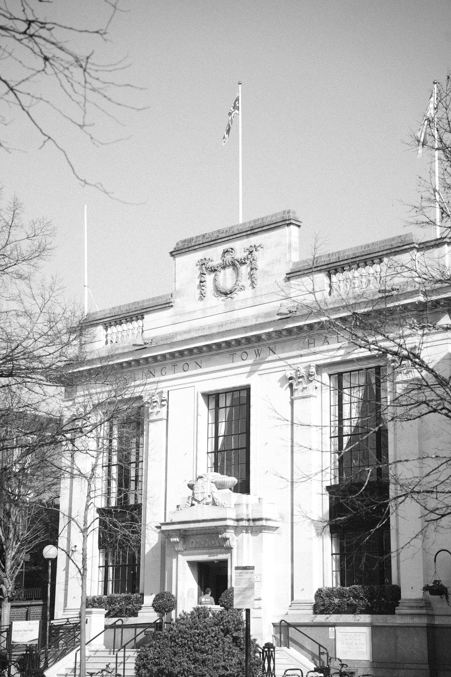 Black and white photo of a stately government building with classical architecture, flag pole, and ornate details.