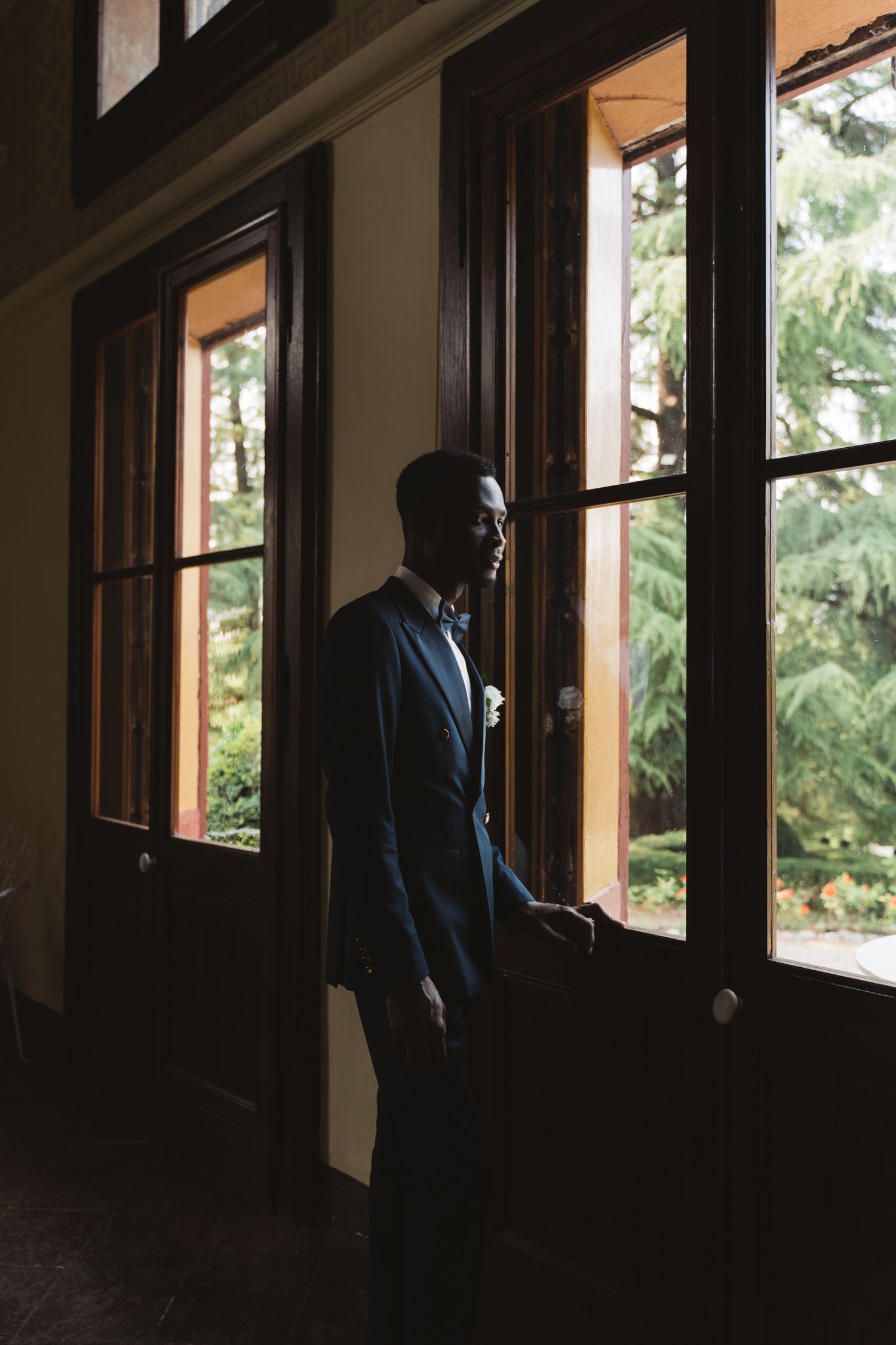Dramatic silhouette of figures standing by large windows in dark interior.