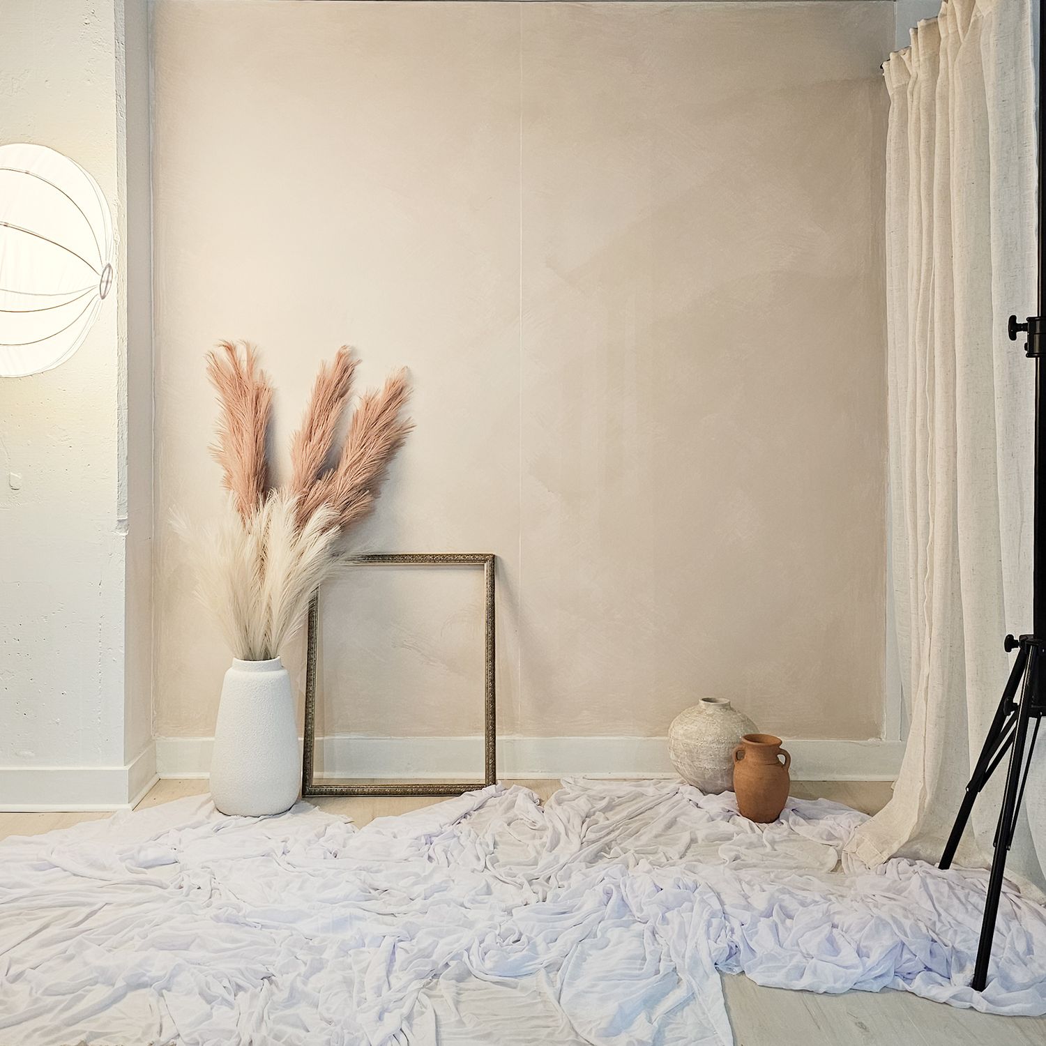 Neutral wall decor with dried pampas grass in white vases against a beige backdrop.