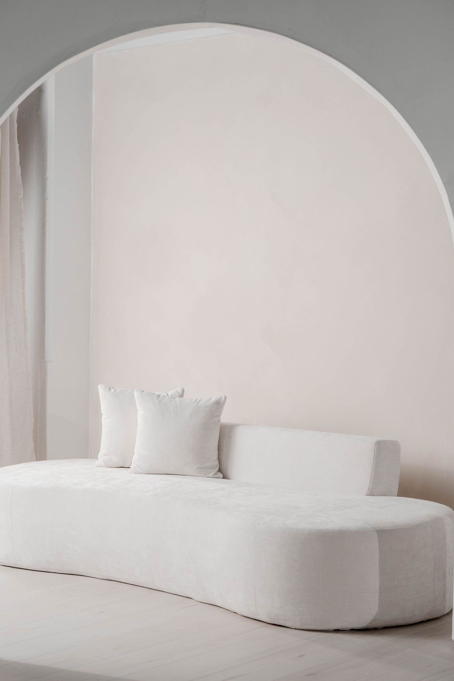 Curved white seating installation beneath an arched wall creating a minimalist architectural statement.